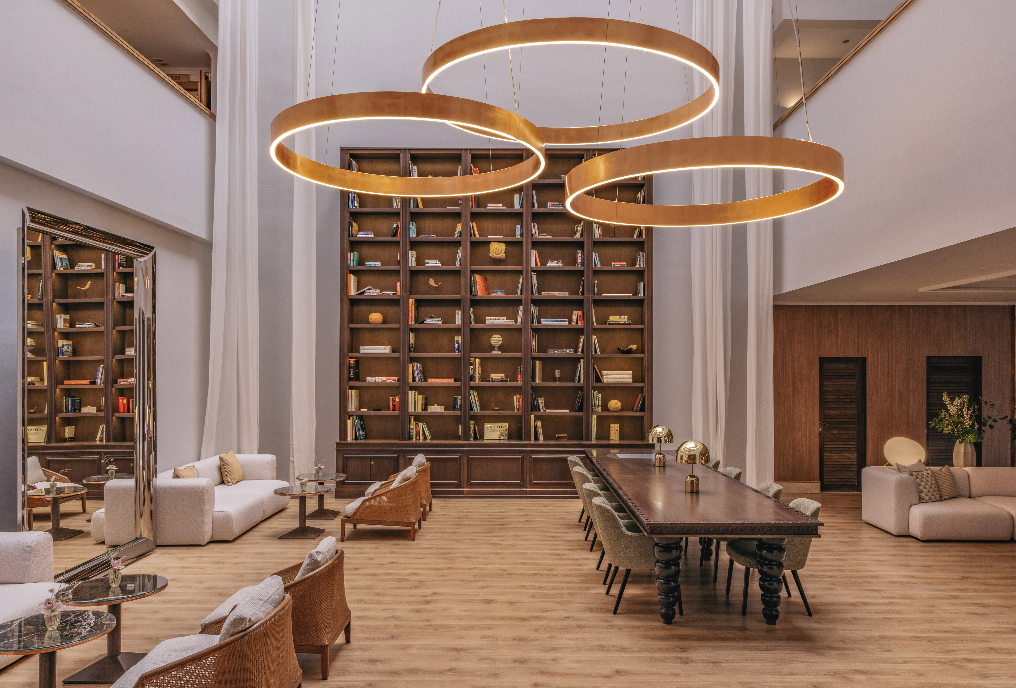 Luxury lounge library with circular chandeliers and extensive bookshelf.