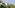 Modern resort villa by tranquil lake, lush palm trees, mountain view.