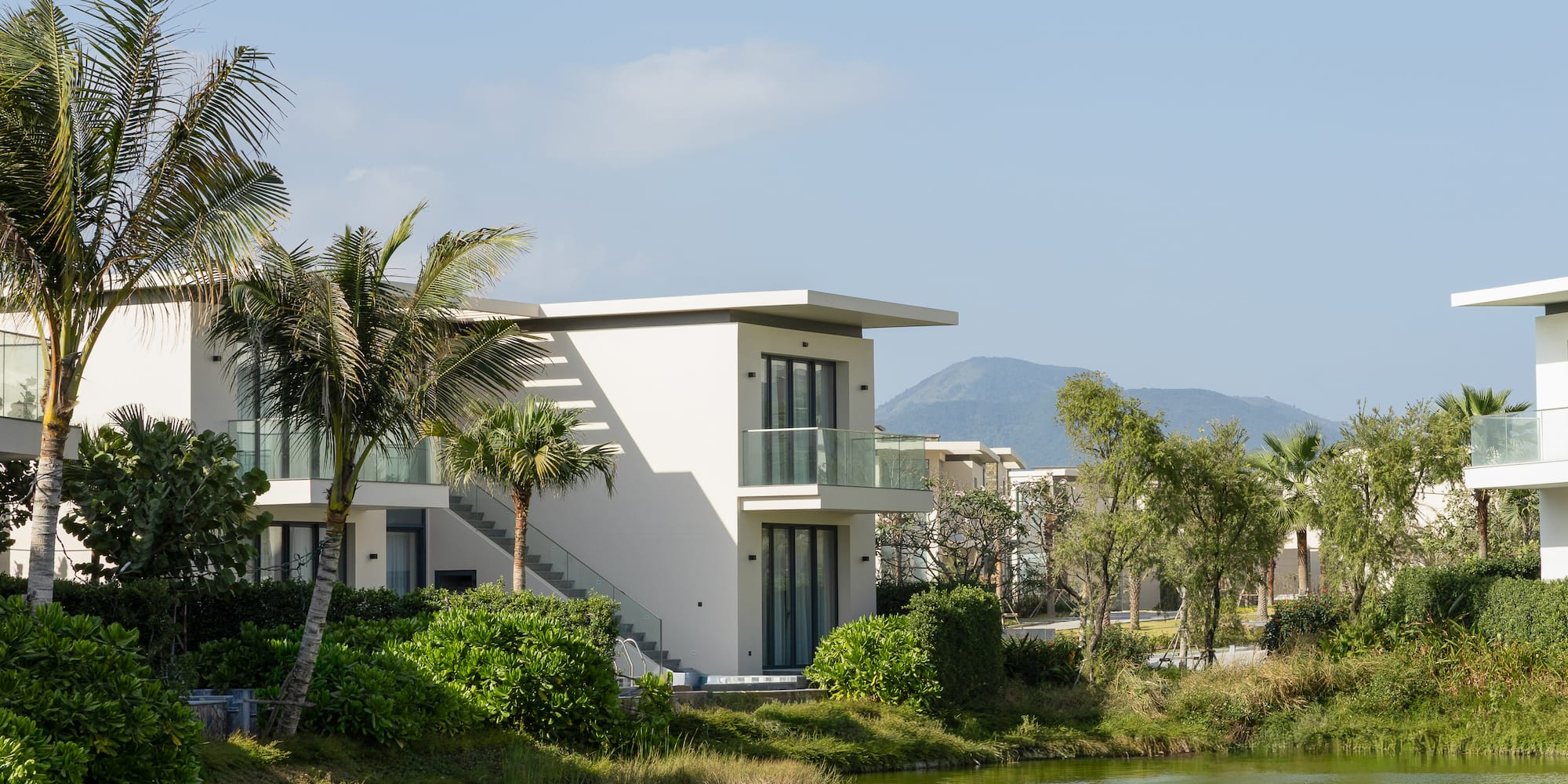 a white building with trees and a body of water