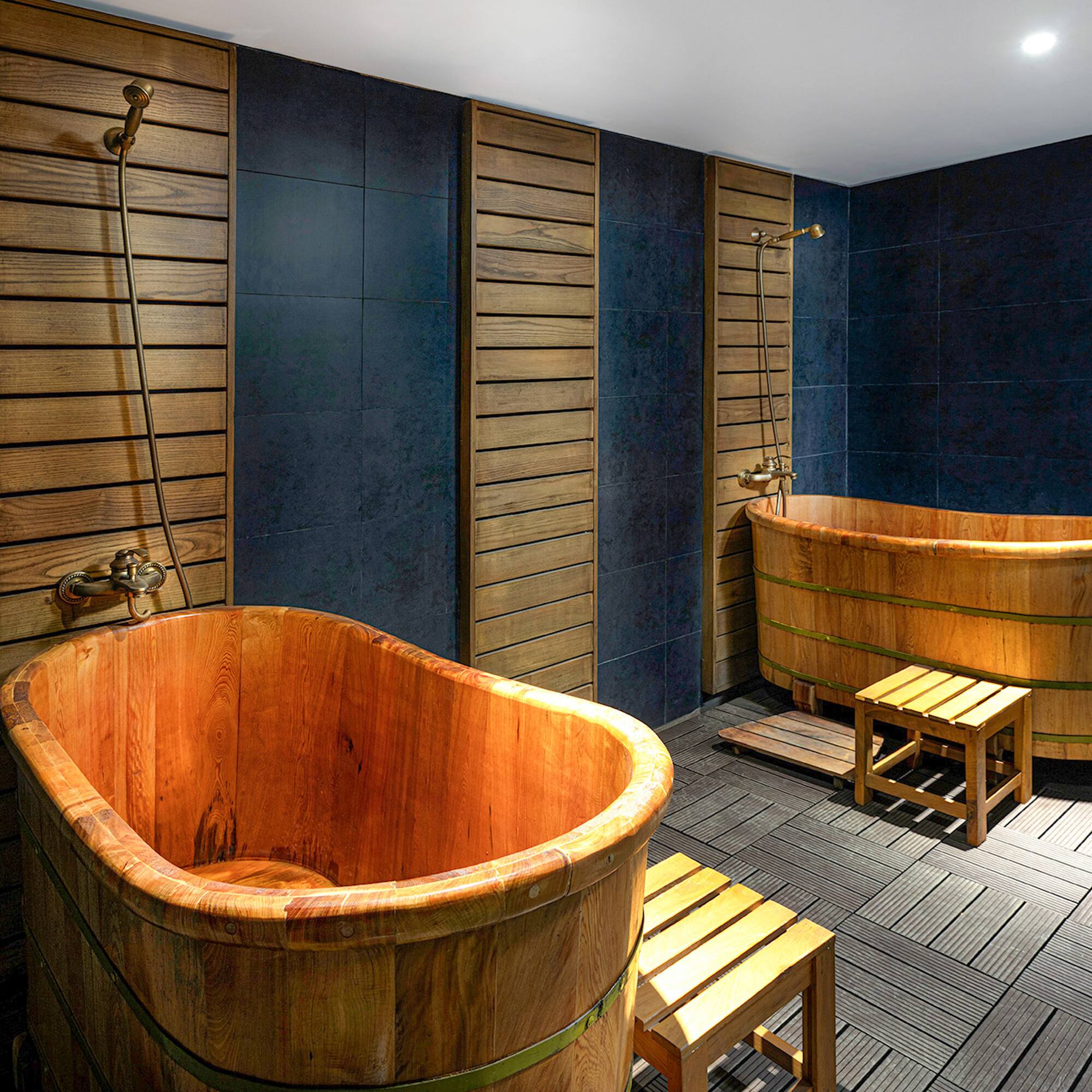 a bathroom with wooden tubs and a bench