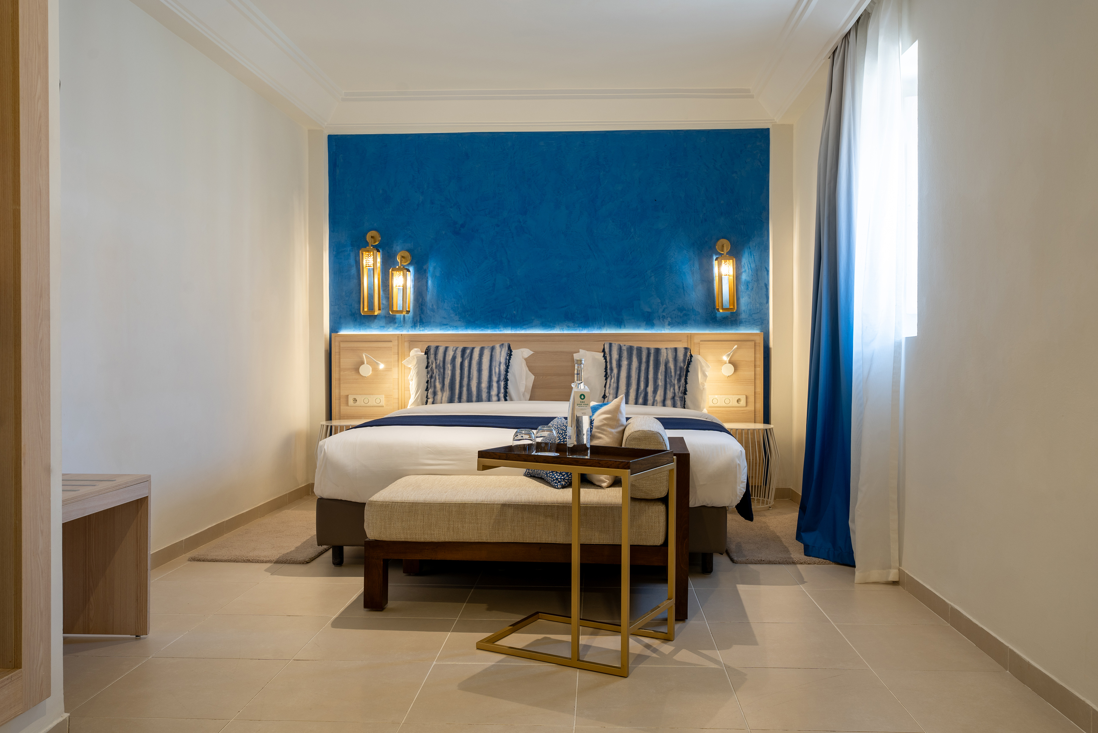 Hotel bedroom with blue accent wall, king bed, and modern decor.