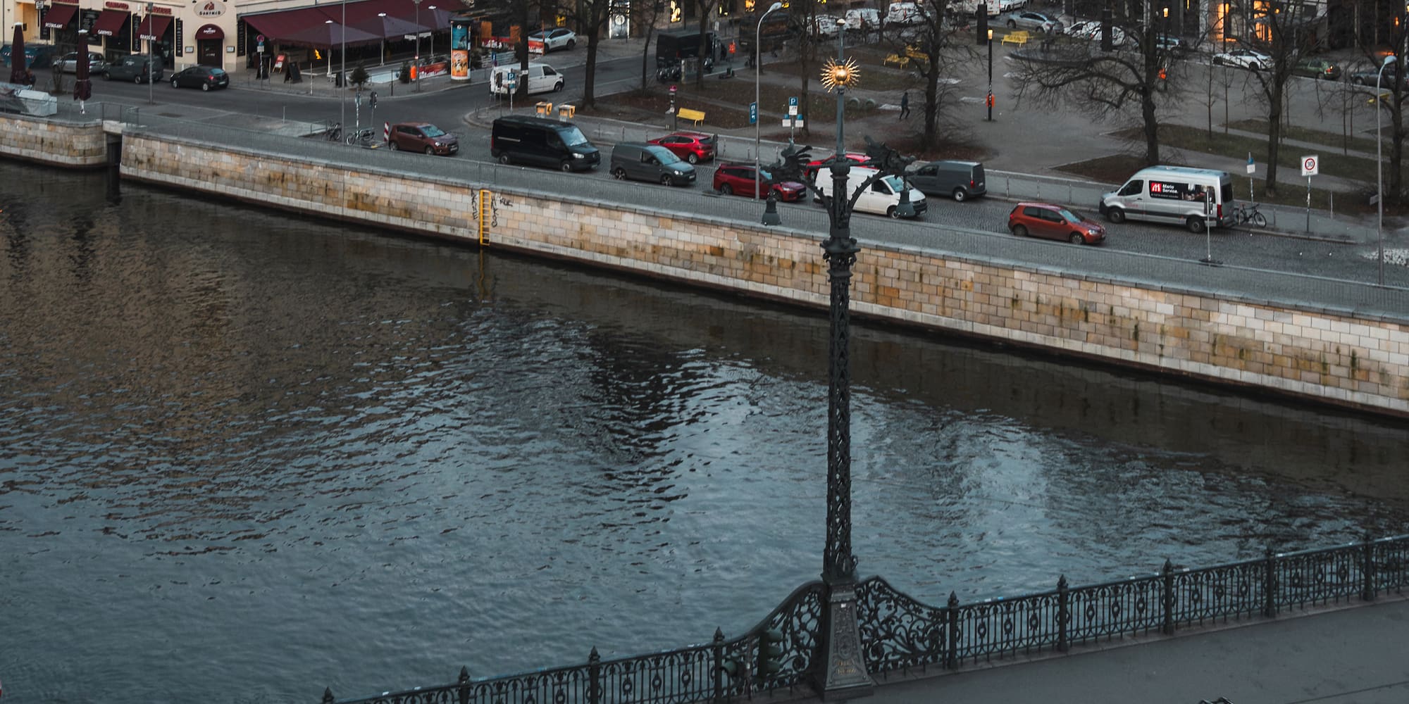 a river with a bridge and cars and buildings