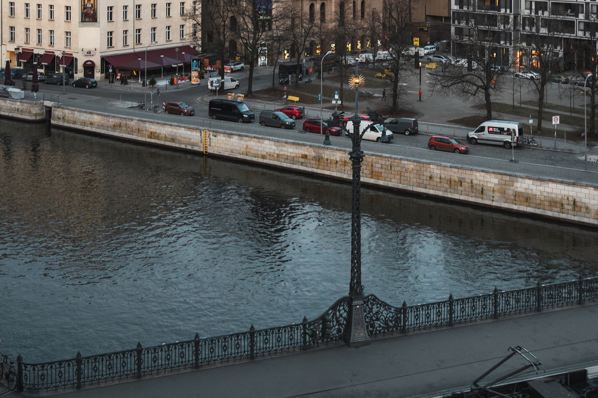 a river with a bridge and cars and buildings