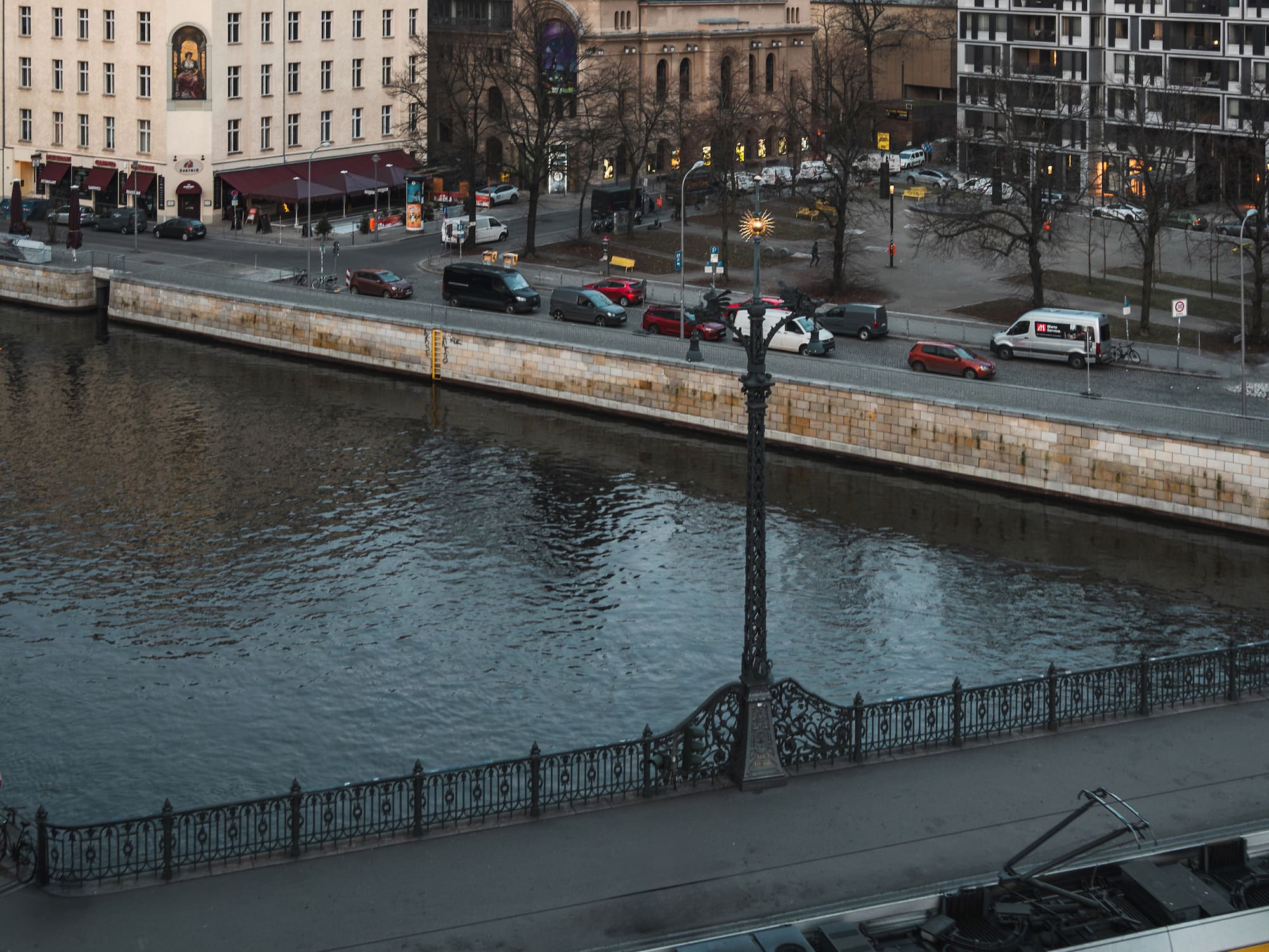 a river with a bridge and cars and buildings