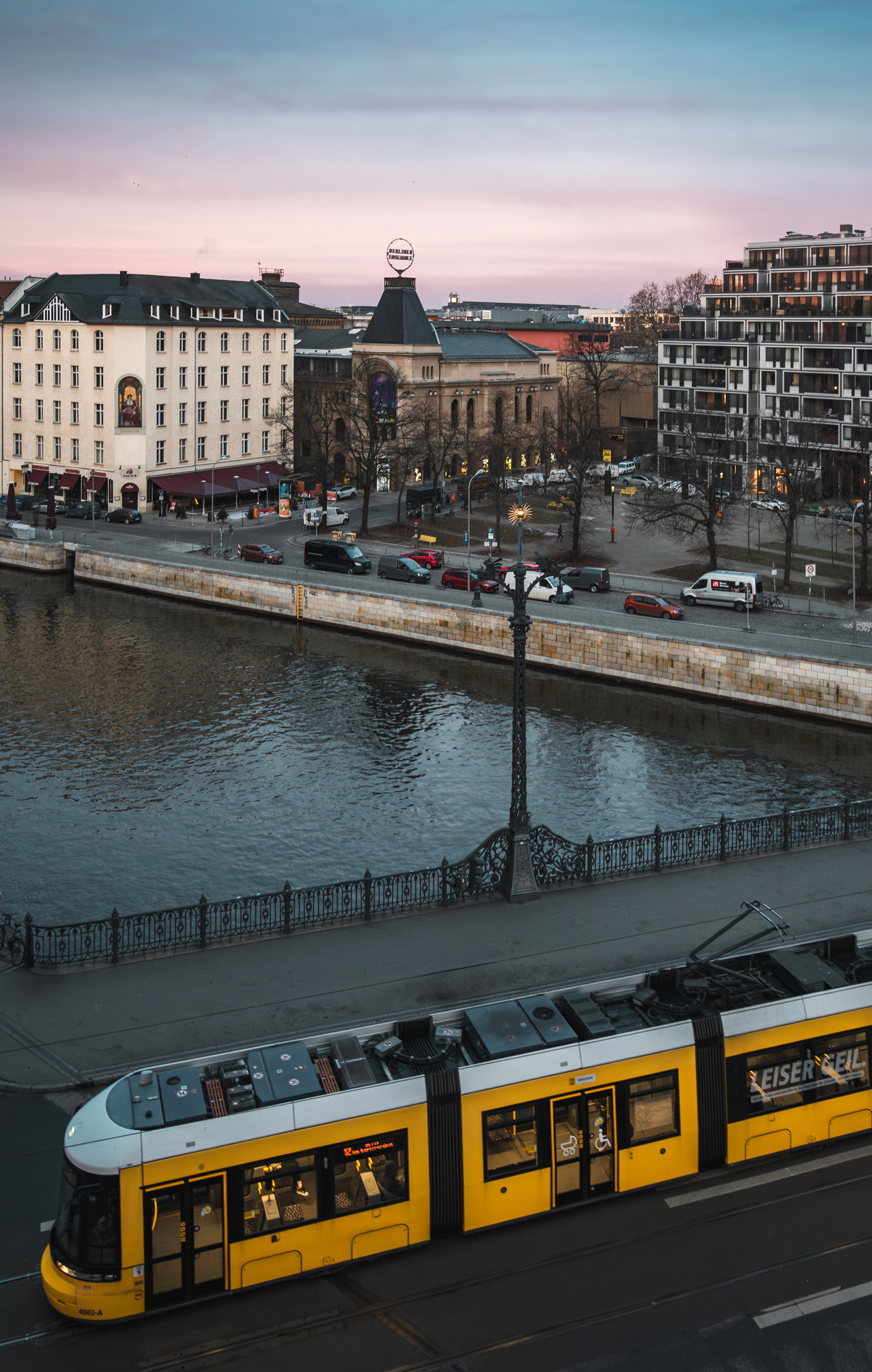 Berlin cityscape at dusk with yellow tram, Spree river, and Berliner Ensemble.