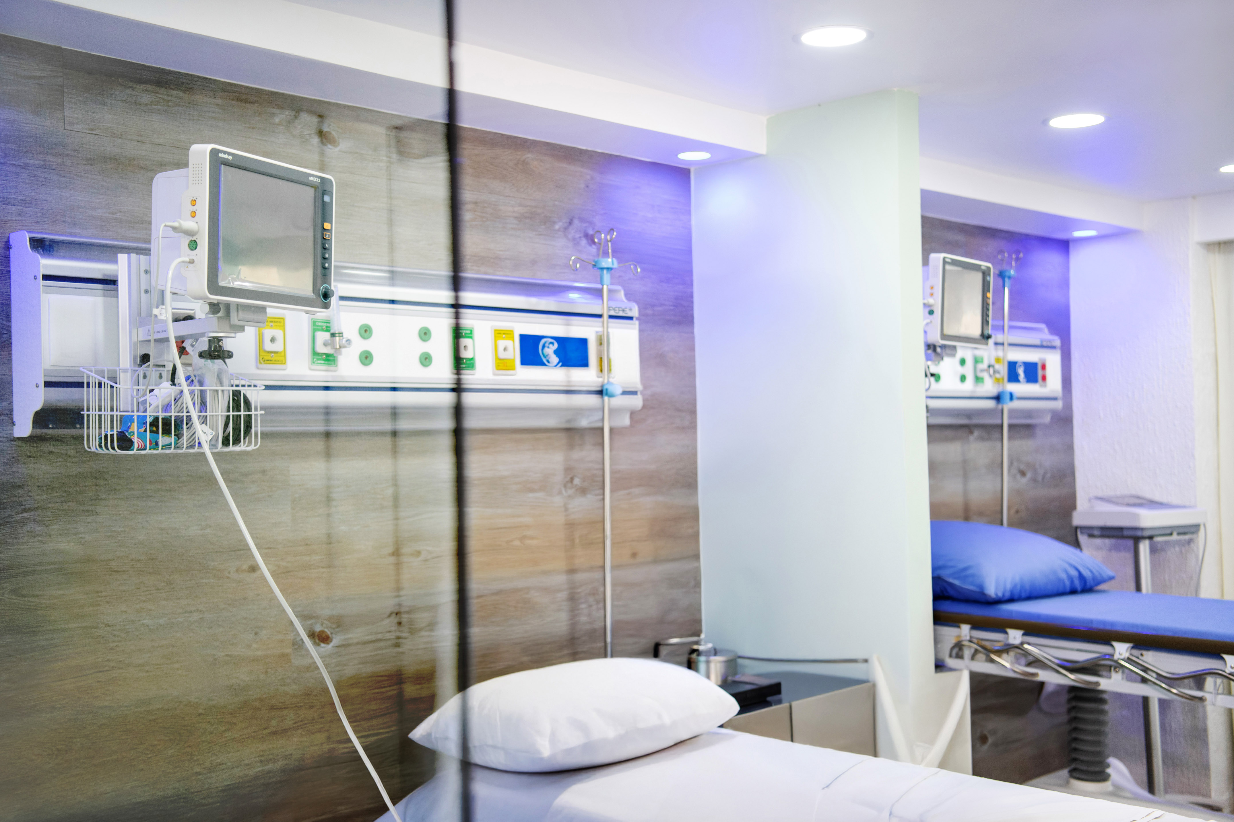 Modern hospital room with patient monitors, IV poles, and hospital beds.