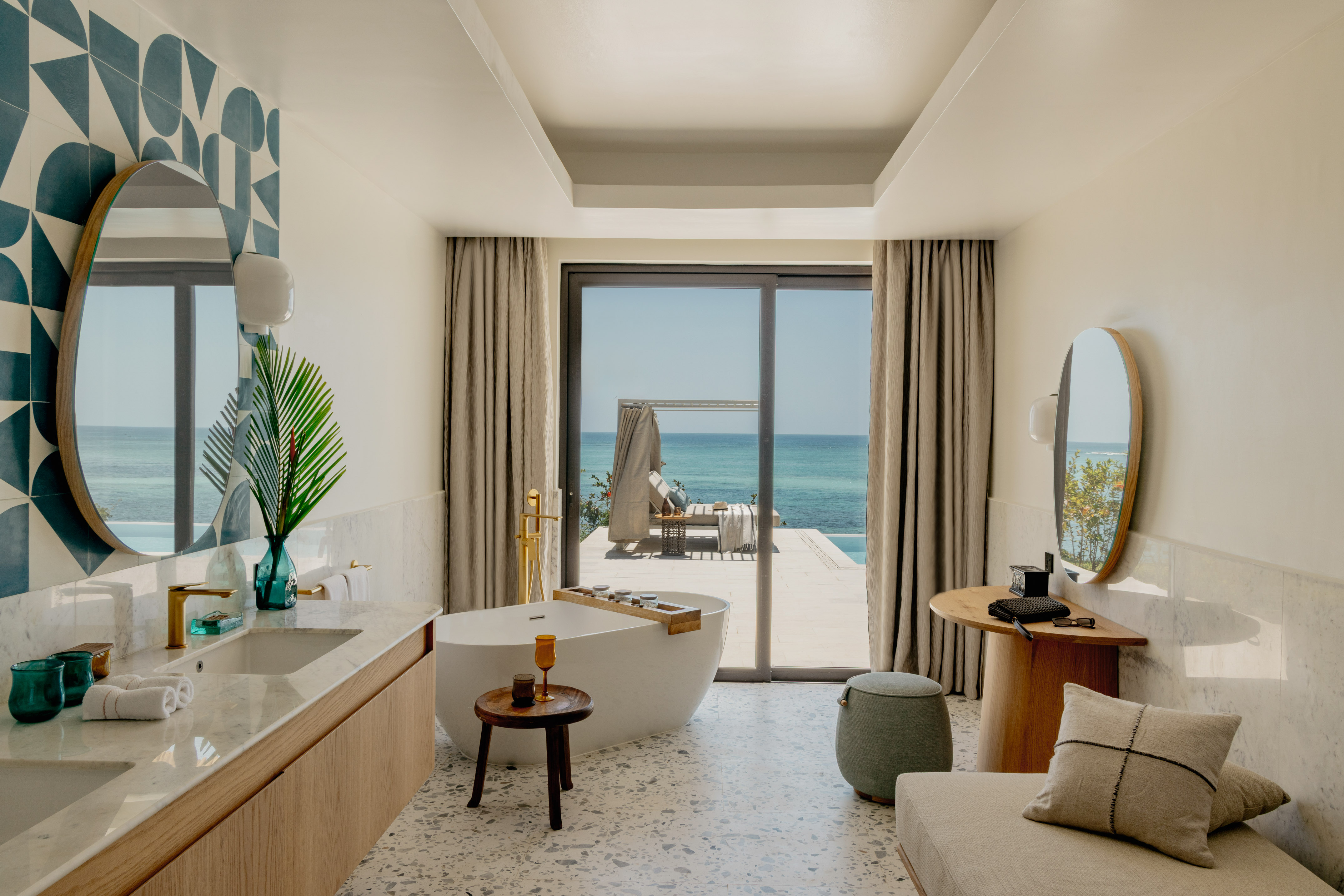 Tropical luxury bathroom with sea view, freestanding tub, and private patio.