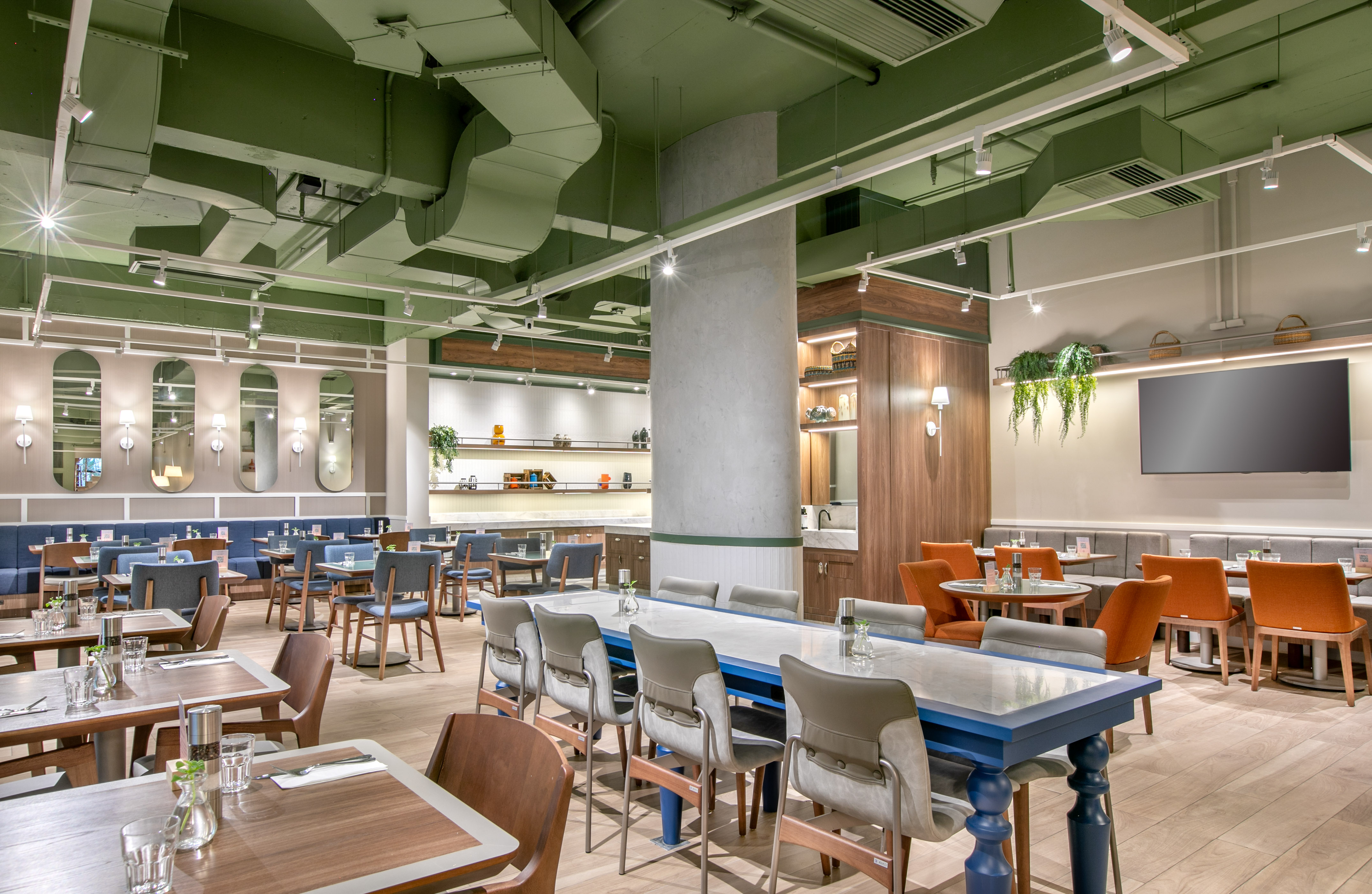 Bright restaurant interior with green ceiling, modern tables, and varied seating.
