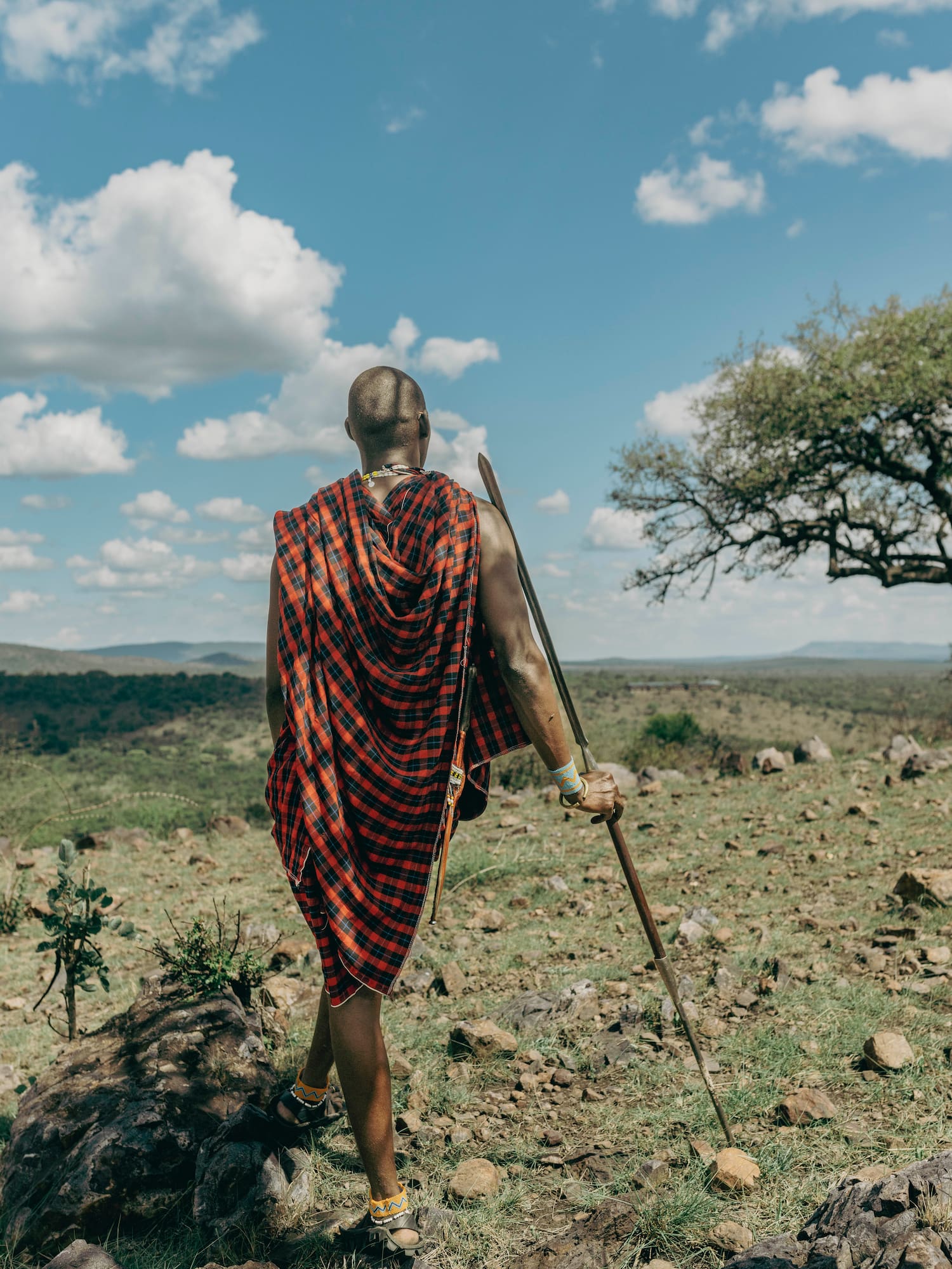 a man in a red and black robe walking in a field