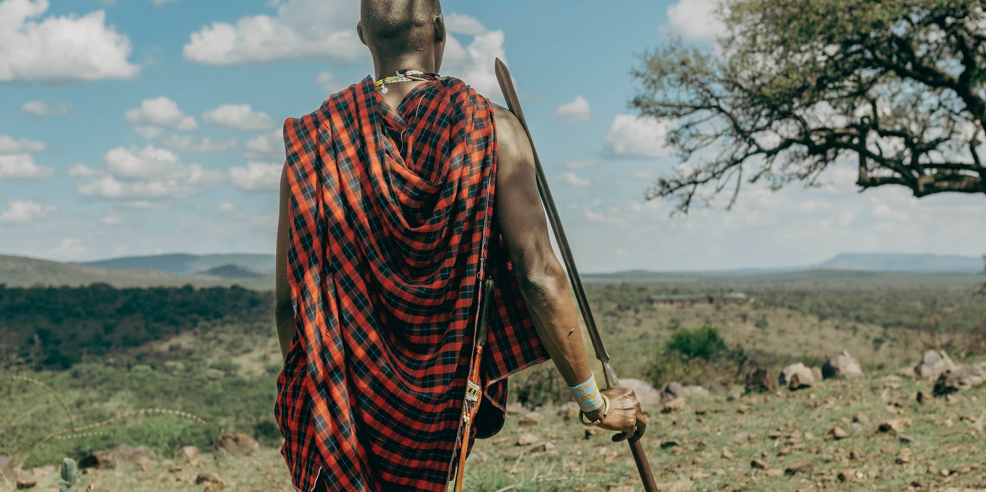a man in a red and black robe walking in a field