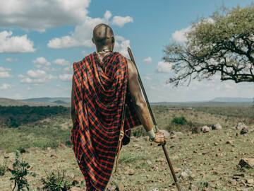 a man in a red and black robe walking in a field