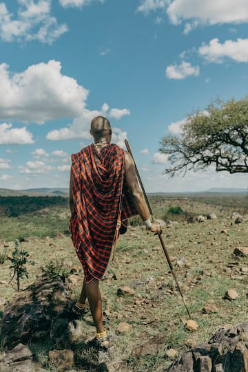 a man in a red and black robe walking in a field