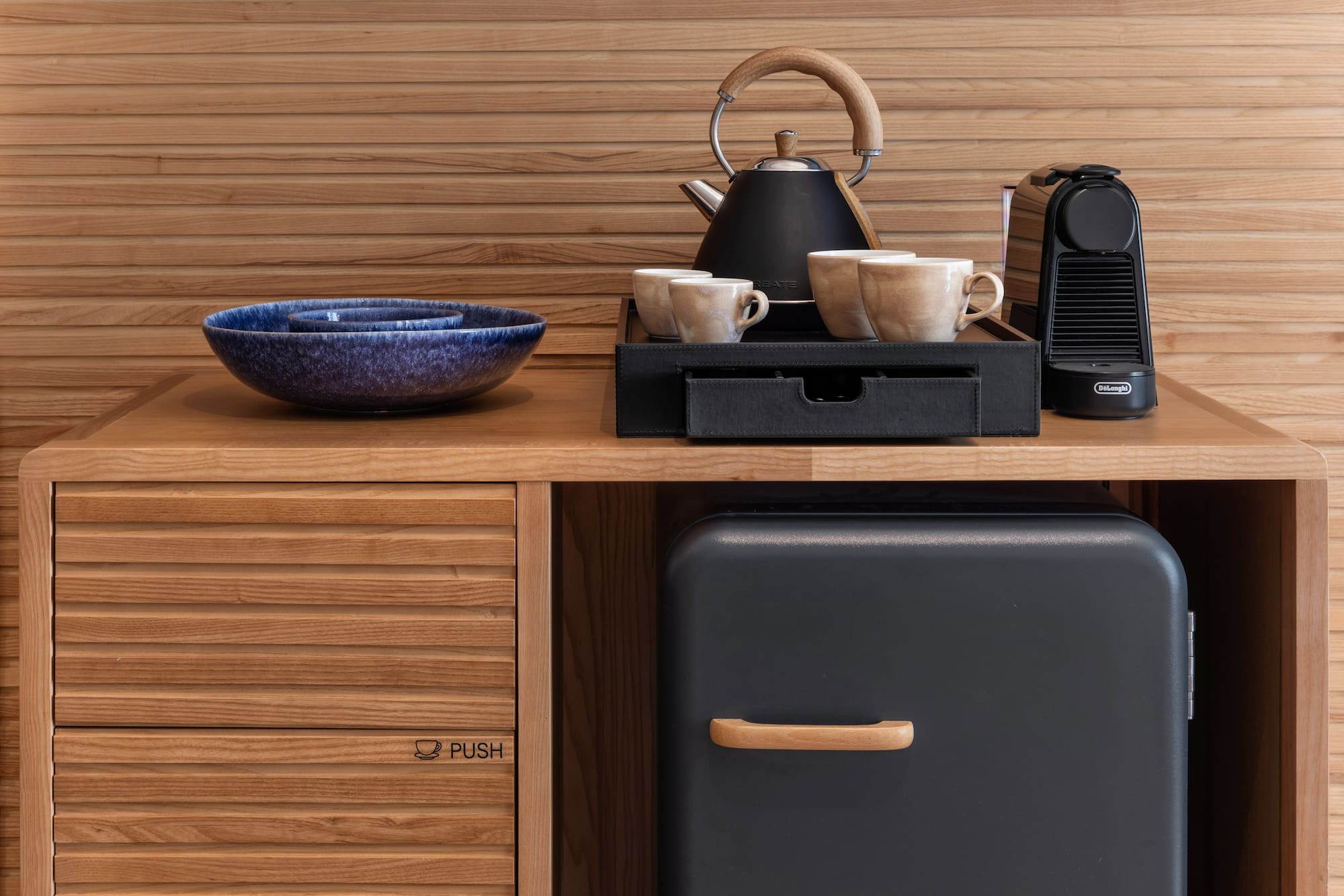 Comodidades de hotel: cafetera Nespresso, tetera, tazas, minibar y aperitivos.