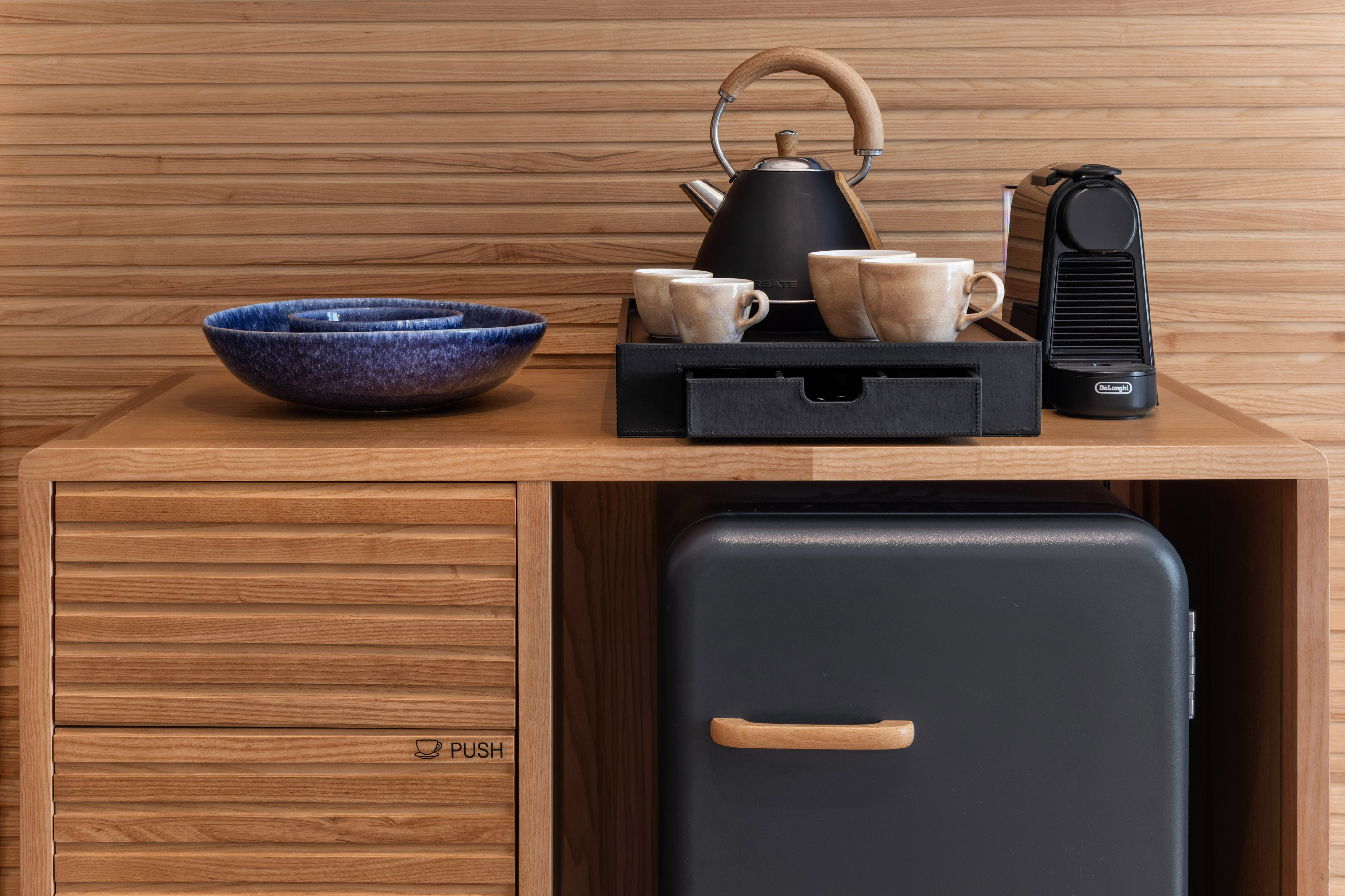 Comodidades de hotel: cafetera Nespresso, tetera, tazas, minibar y aperitivos.