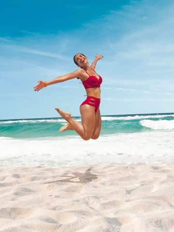 a woman in a garment jumping on a beach