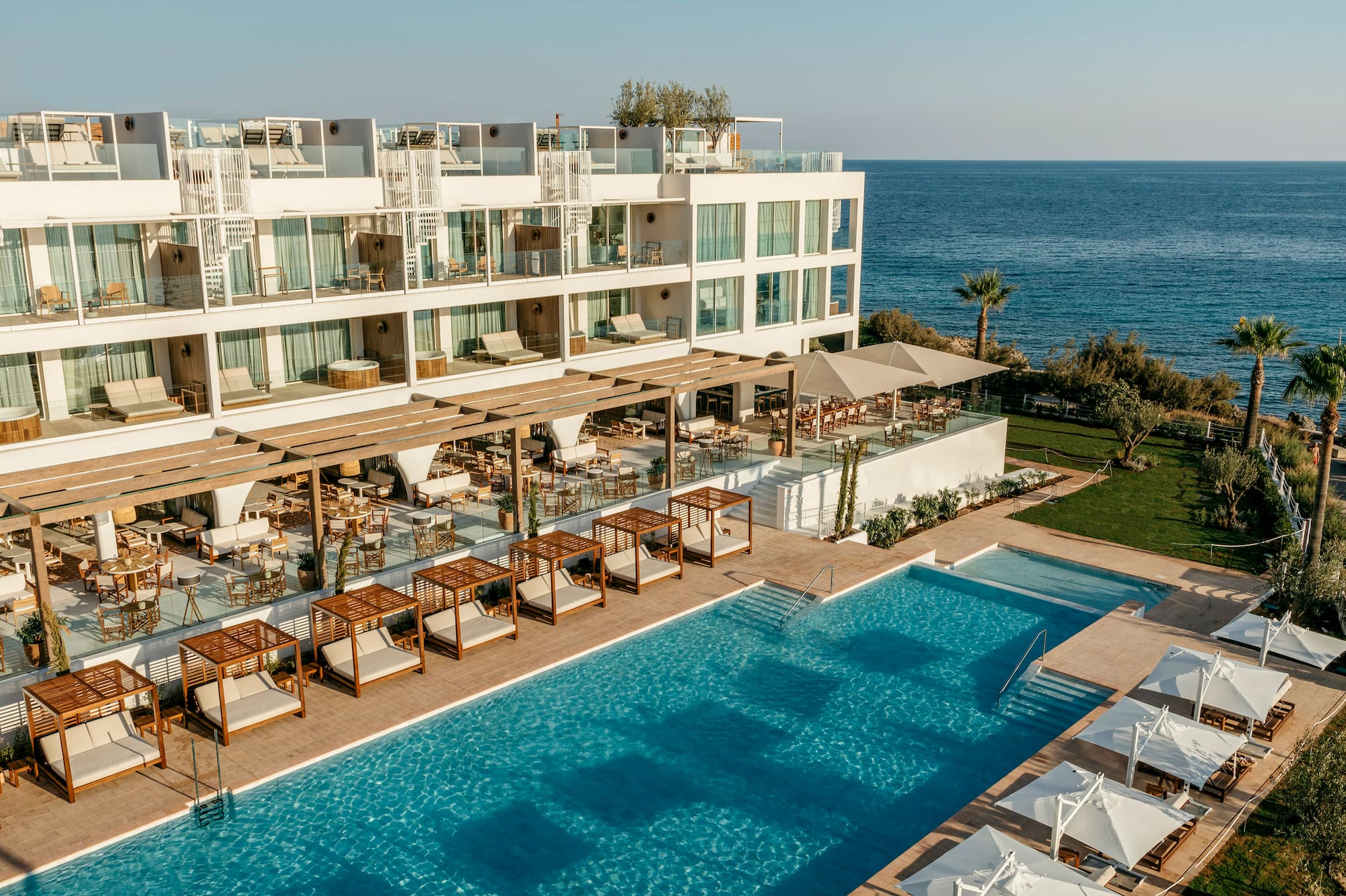 Hotel moderno con piscinas, balinesas, terrazas y vistas al mar.