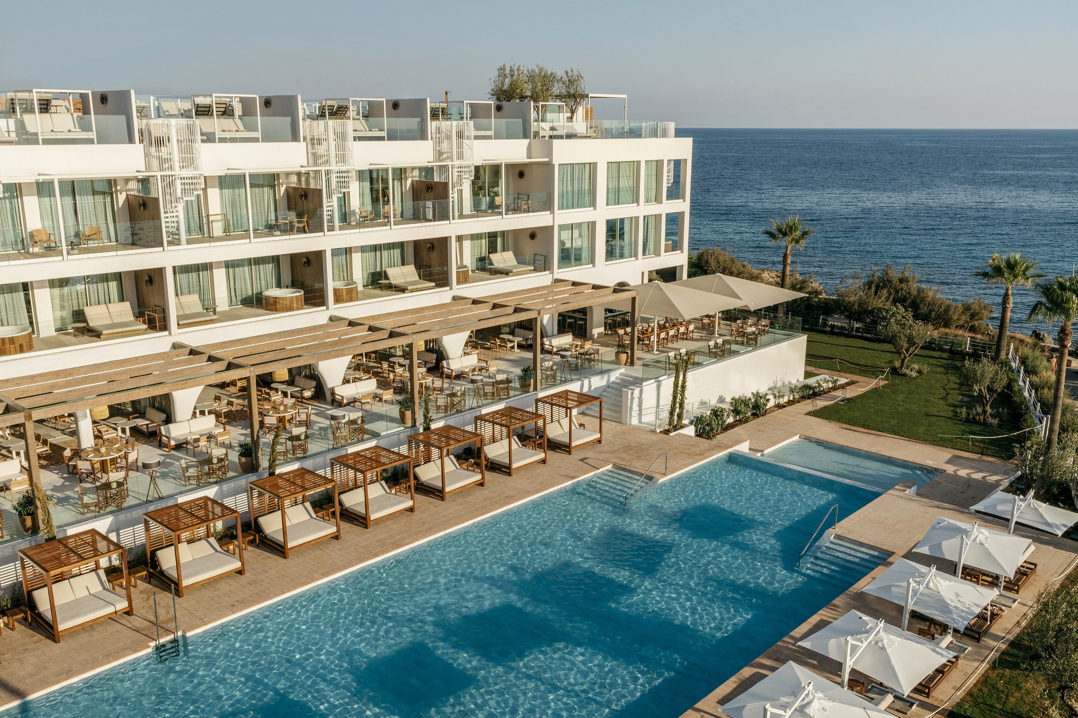 Hotel moderno con piscinas, balinesas, terrazas y vistas al mar.