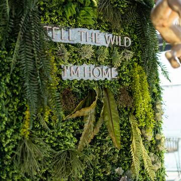 a sign on a wall of plants