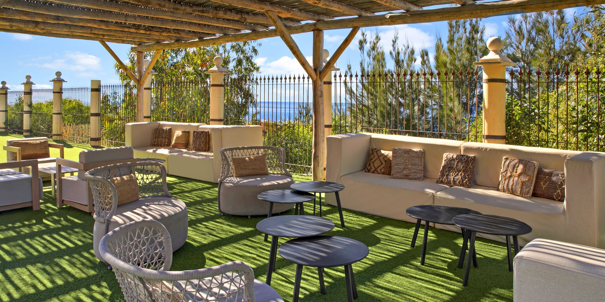 Pergola-covered outdoor lounge with comfortable seating and ocean view.
