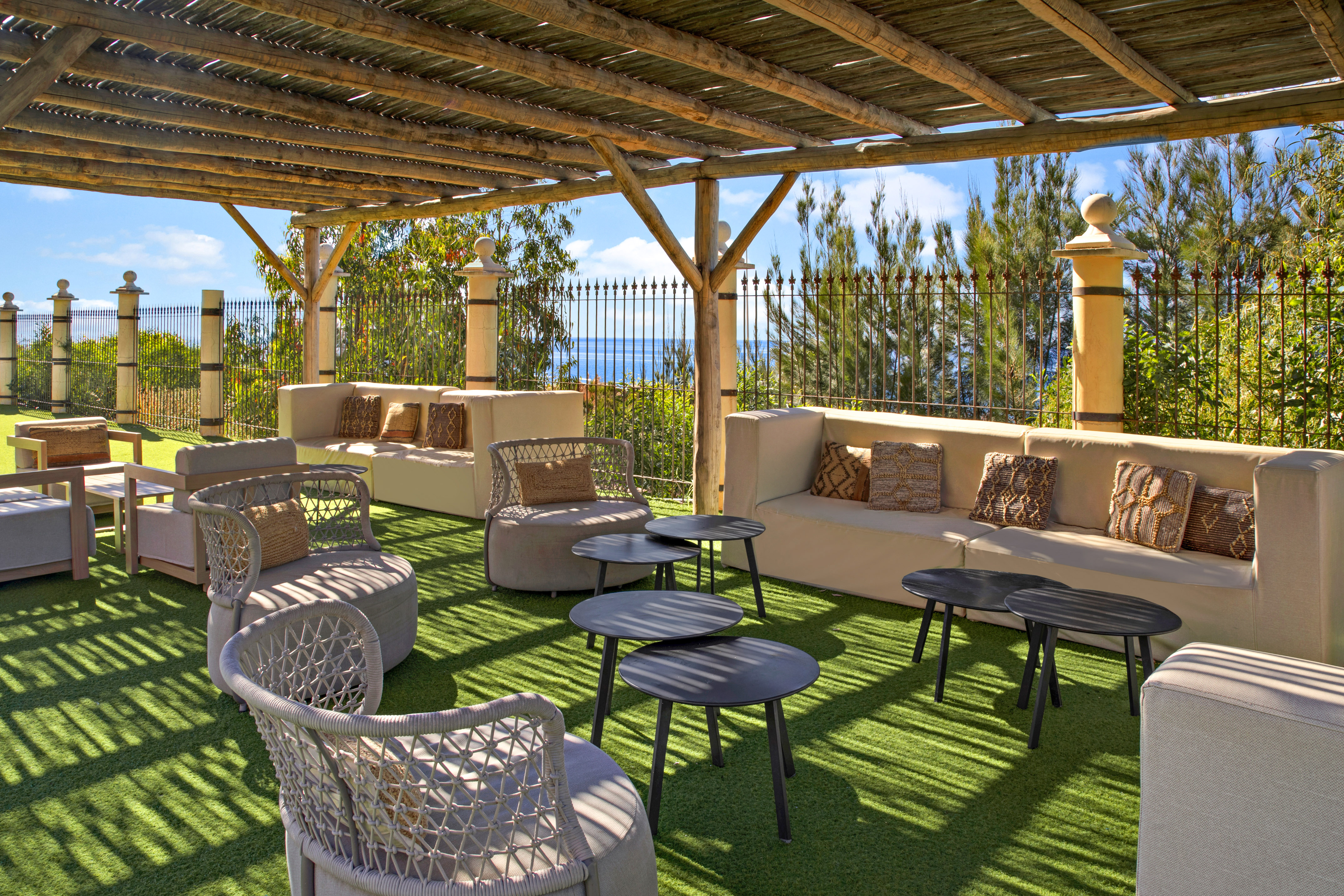 Pergola-covered outdoor lounge with comfortable seating and ocean view.