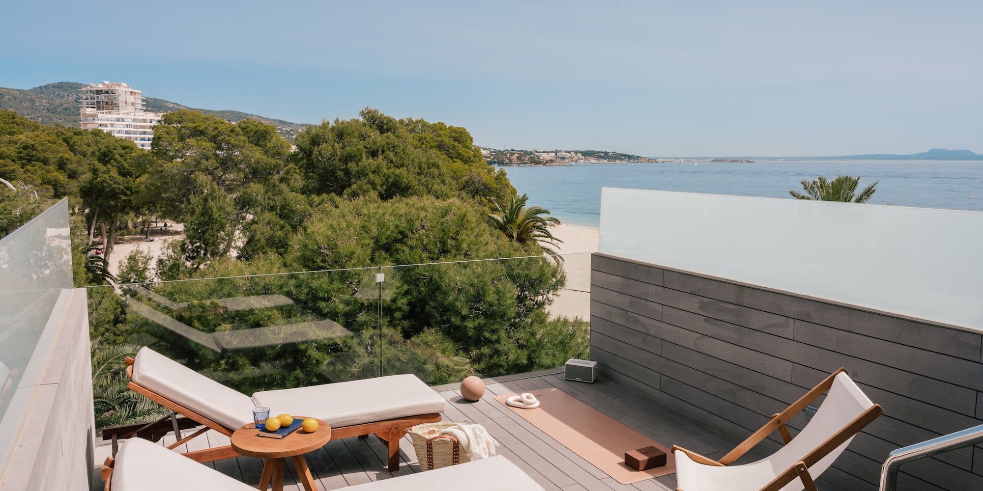 Coastal rooftop terrace with ocean view, lounge chairs, yoga mat.