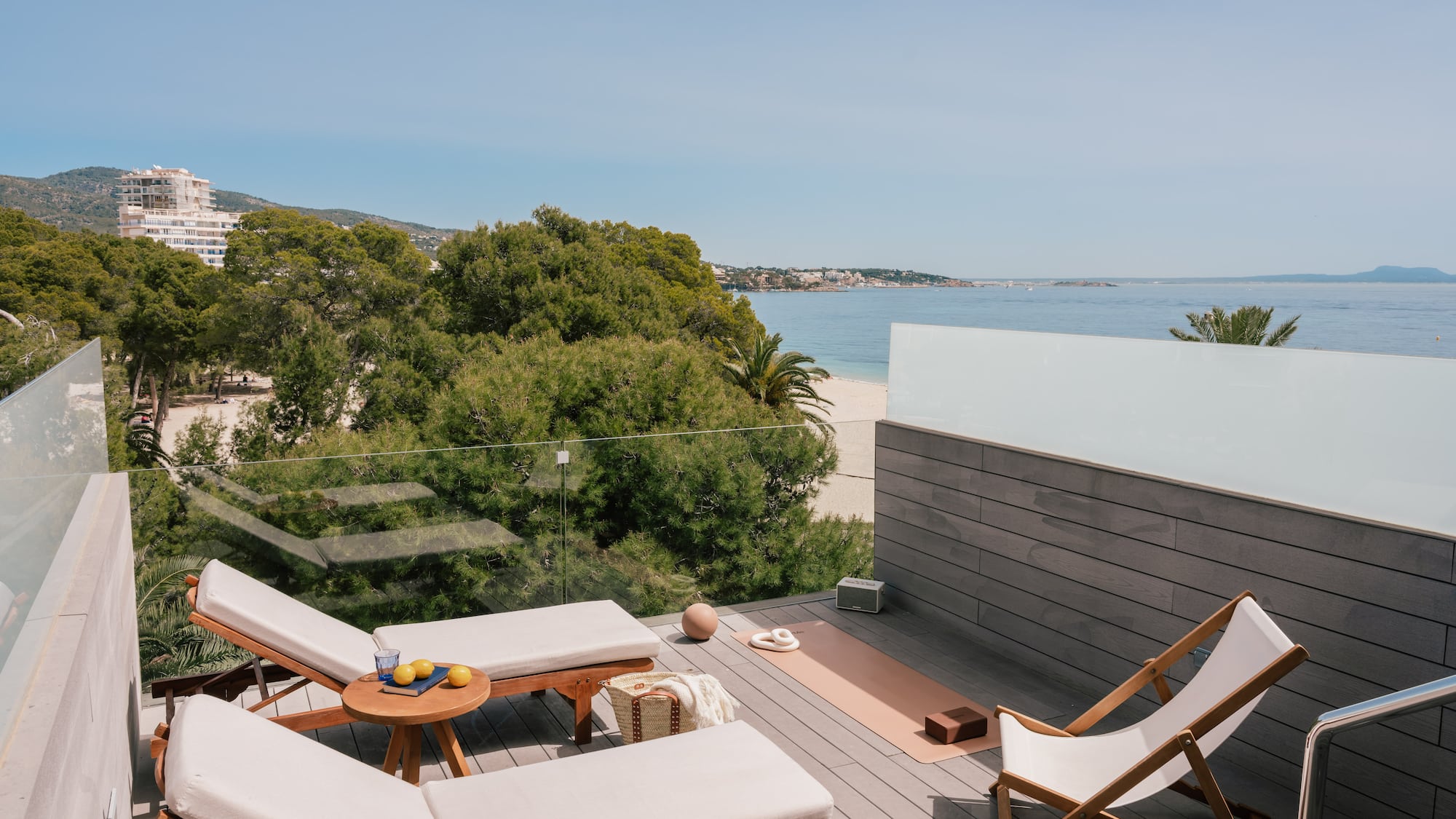 Coastal rooftop terrace with ocean view, lounge chairs, yoga mat.