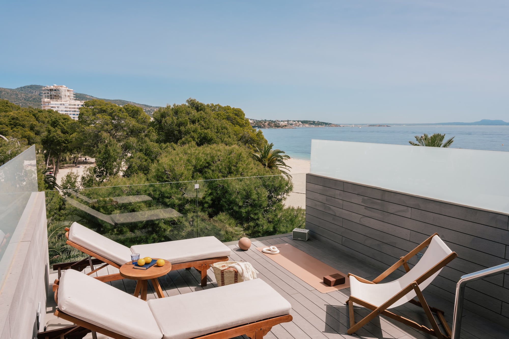 Coastal rooftop terrace with ocean view, lounge chairs, yoga mat.