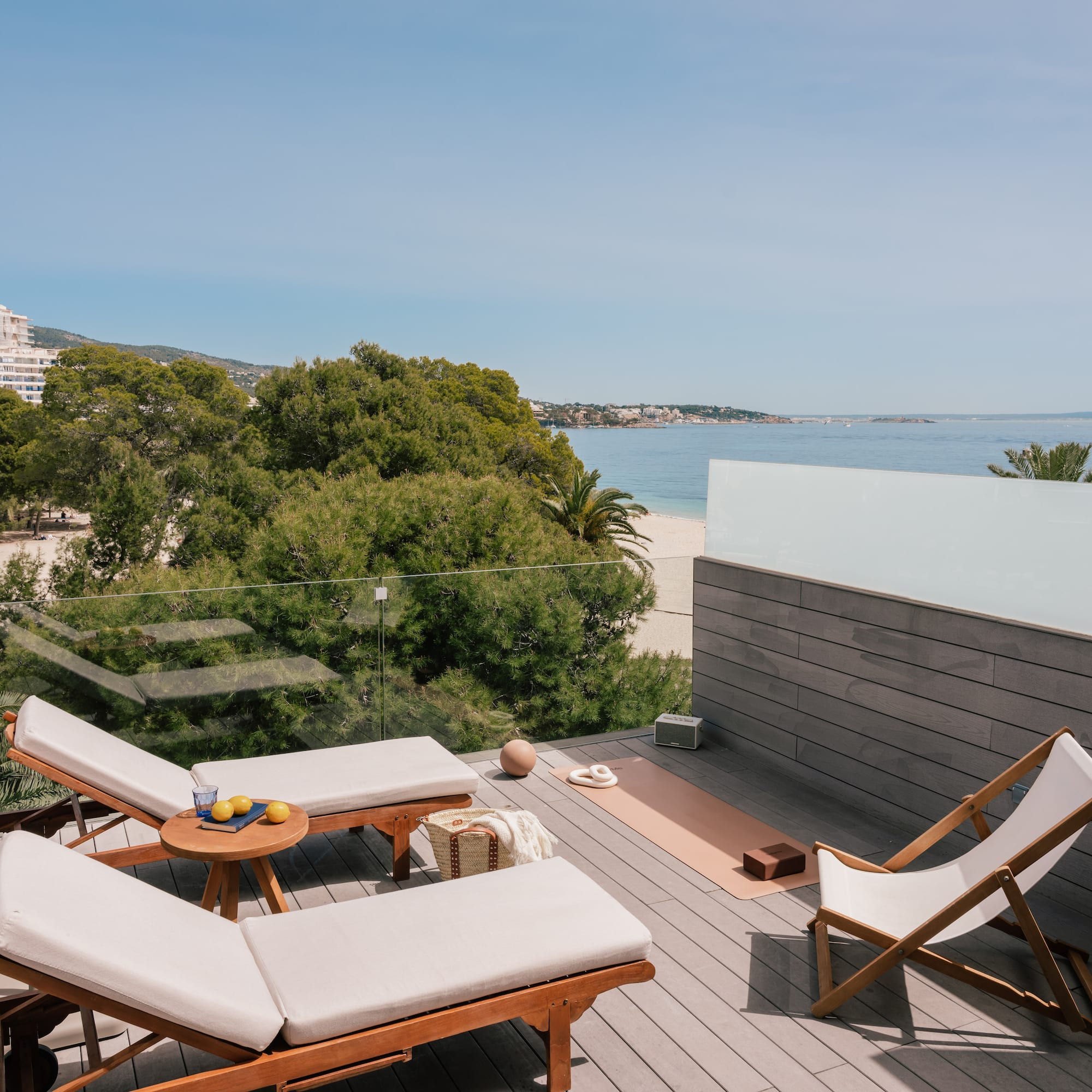 Coastal rooftop terrace with ocean view, lounge chairs, yoga mat.