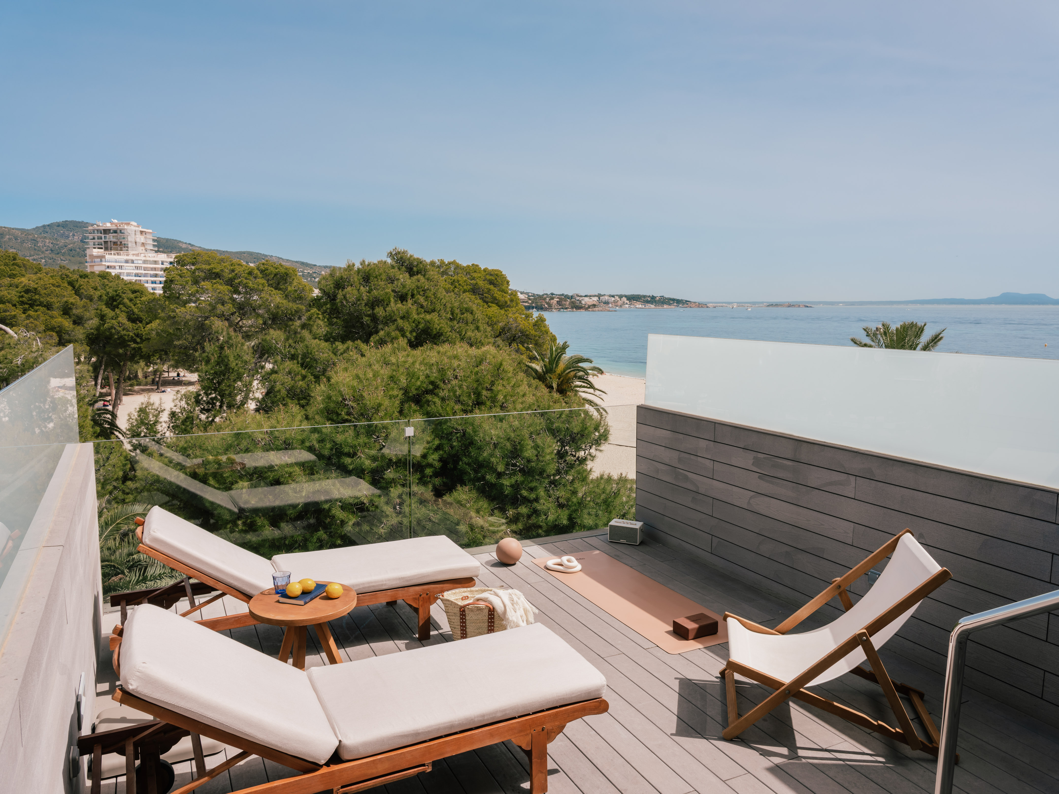 Coastal rooftop terrace with ocean view, lounge chairs, yoga mat.