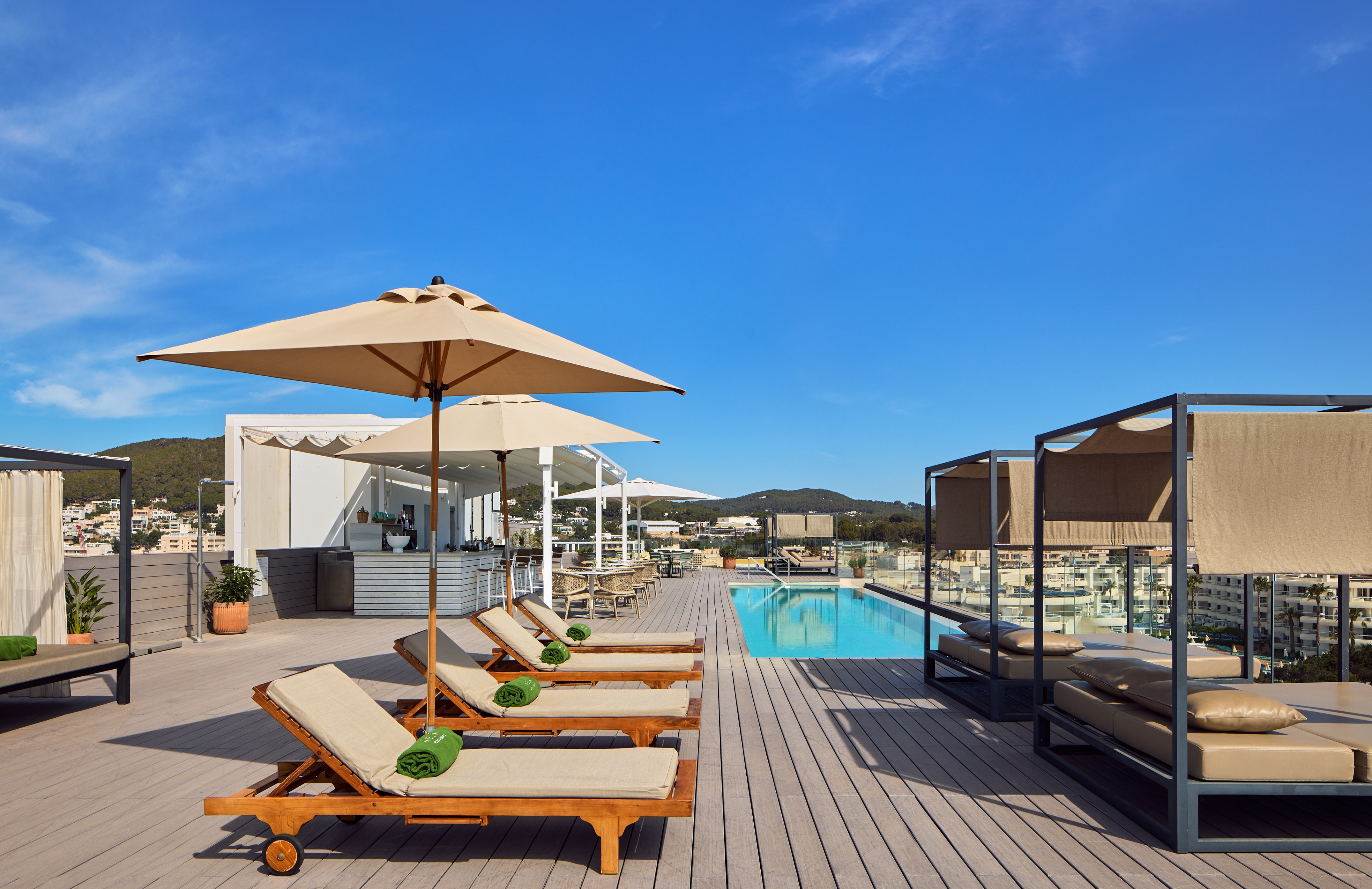Luxury rooftop pool terrace with sun loungers, umbrellas, and daybeds.