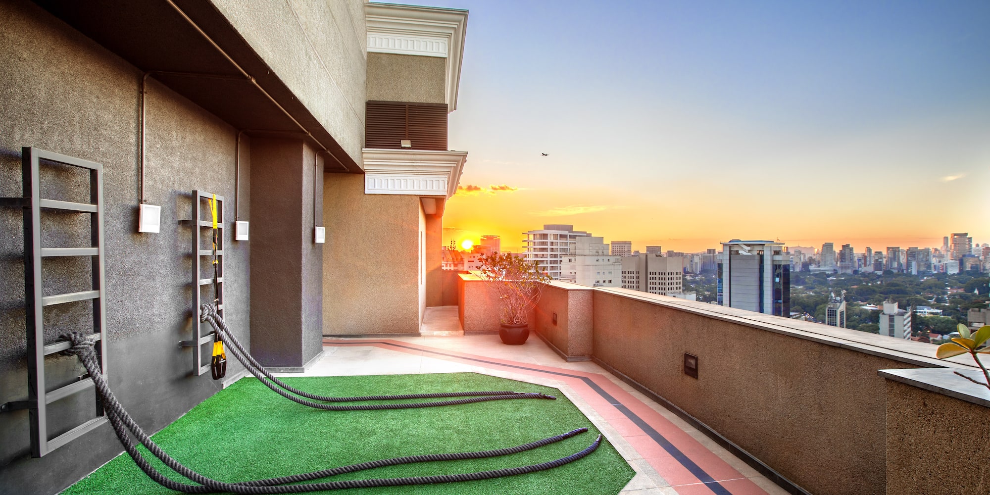 Urban rooftop fitness area with battle ropes, cityscape at sunset.