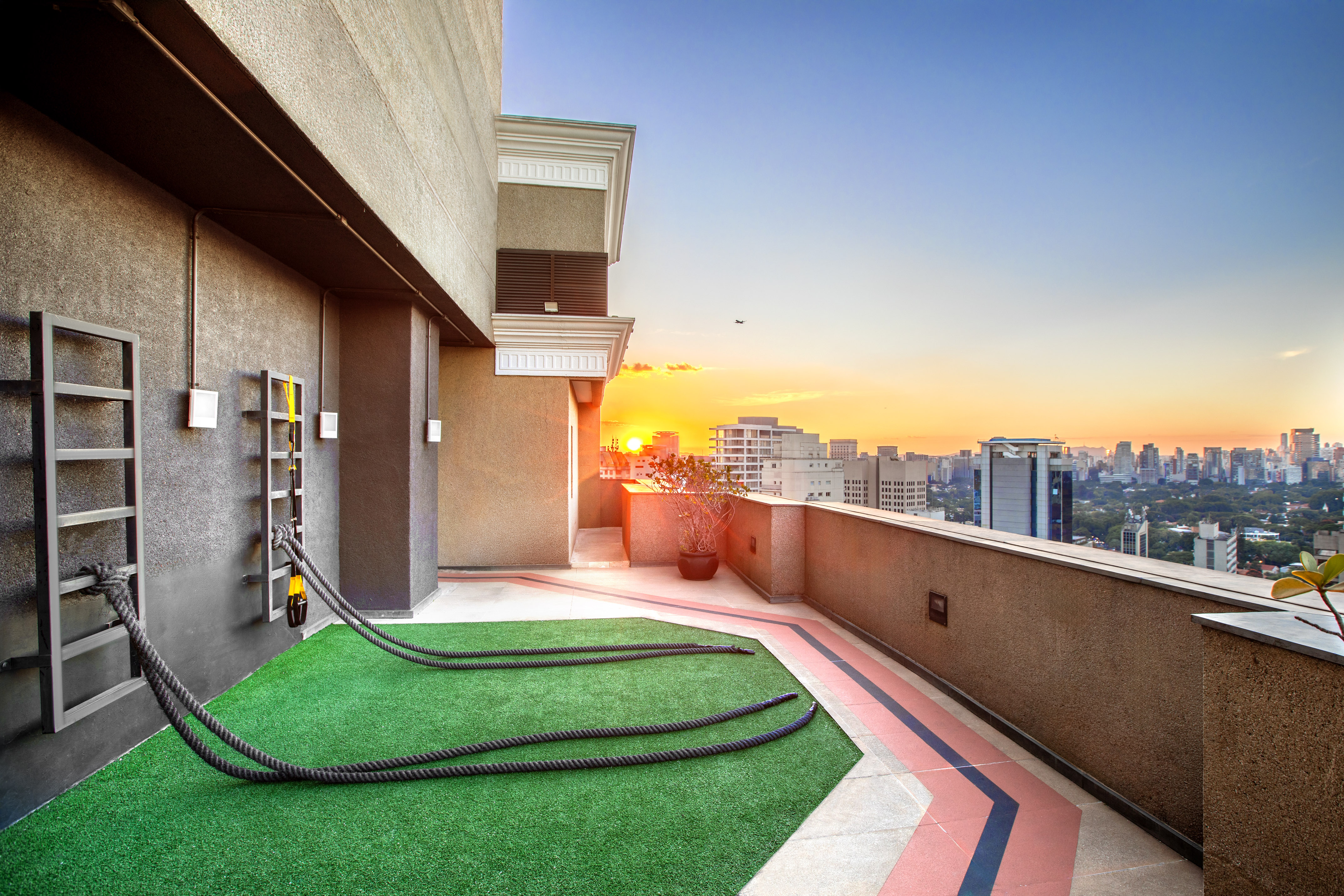 Urban rooftop fitness area with battle ropes, cityscape at sunset.