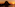 Sunset over ocean with dark rocky island silhouette, reflecting orange sky.