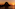 Sunset over ocean with dark rocky island silhouette, reflecting orange sky.
