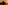 Sunset over ocean with dark rocky island silhouette, reflecting orange sky.