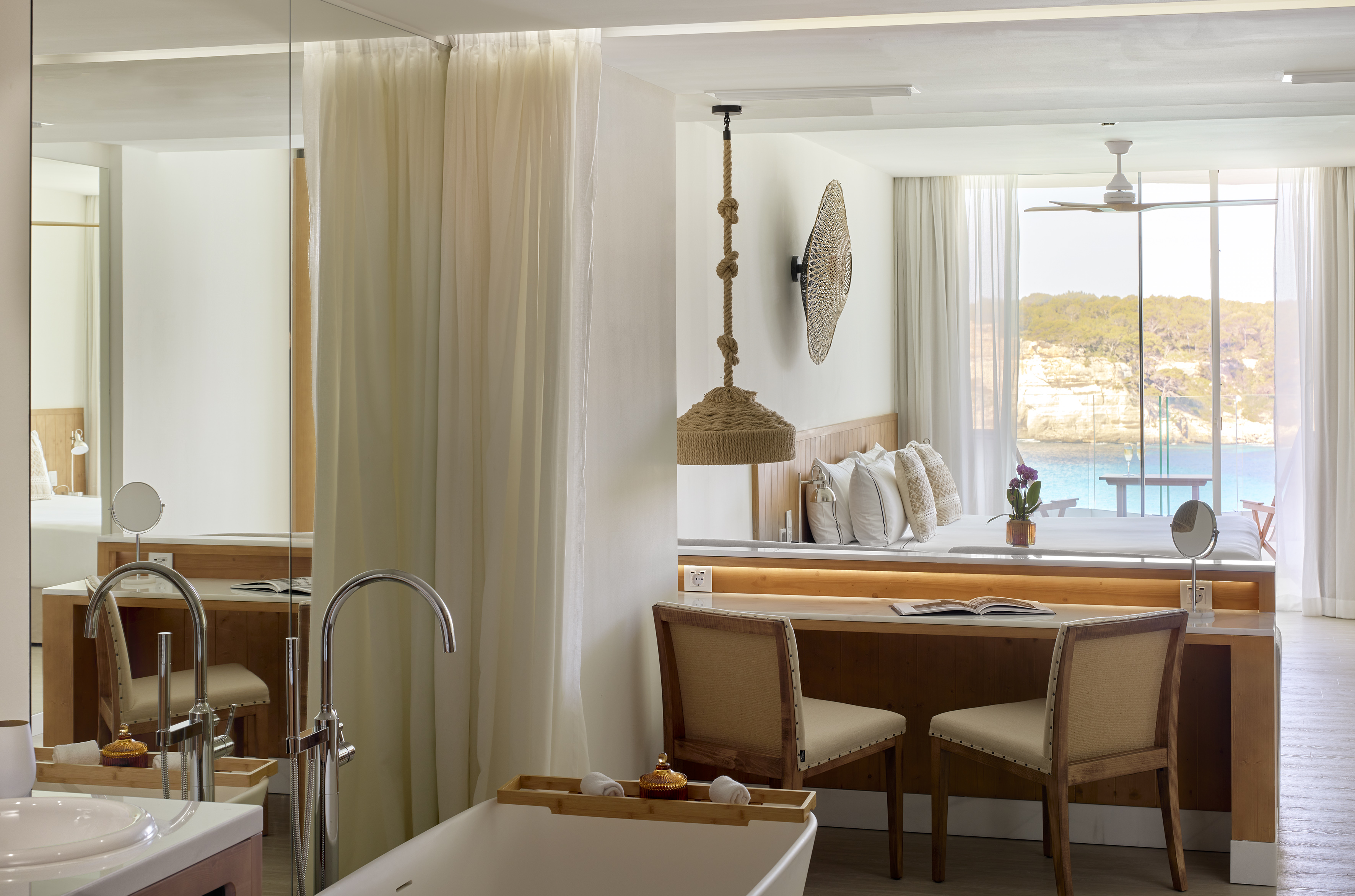 Modern luxury hotel room with ocean view, integrated bedroom and bathroom.