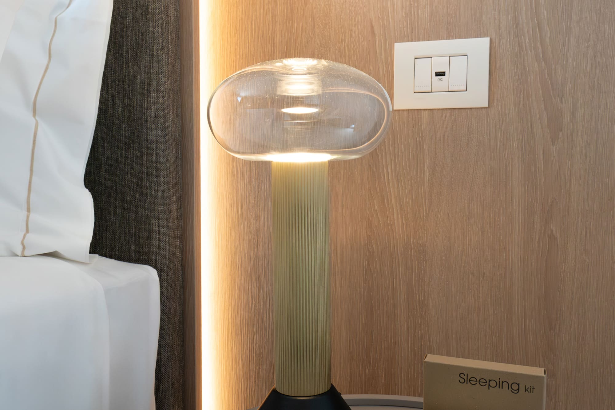a lamp on a table next to a bed
