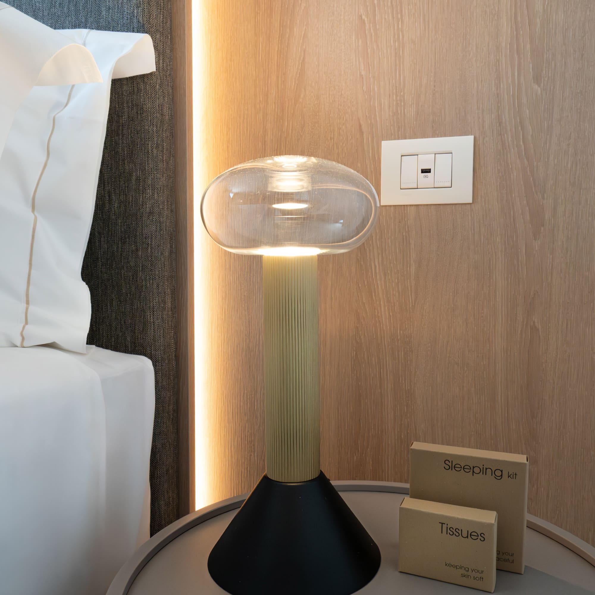 a lamp on a table next to a bed