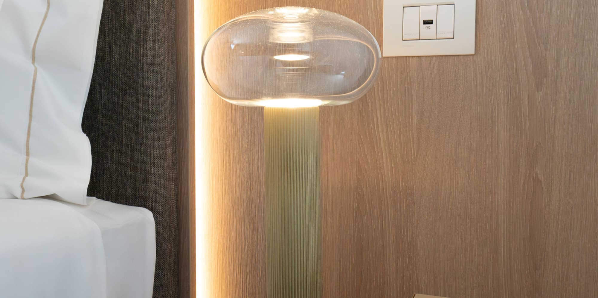 a lamp on a table next to a bed