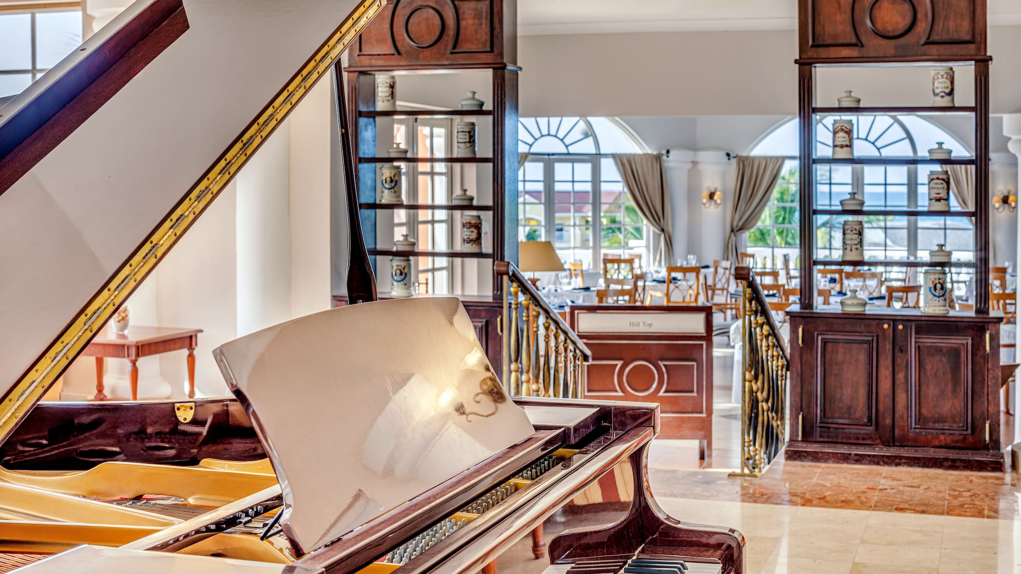 a piano in a room with a staircase and windows