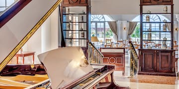 a piano in a room with a staircase and windows
