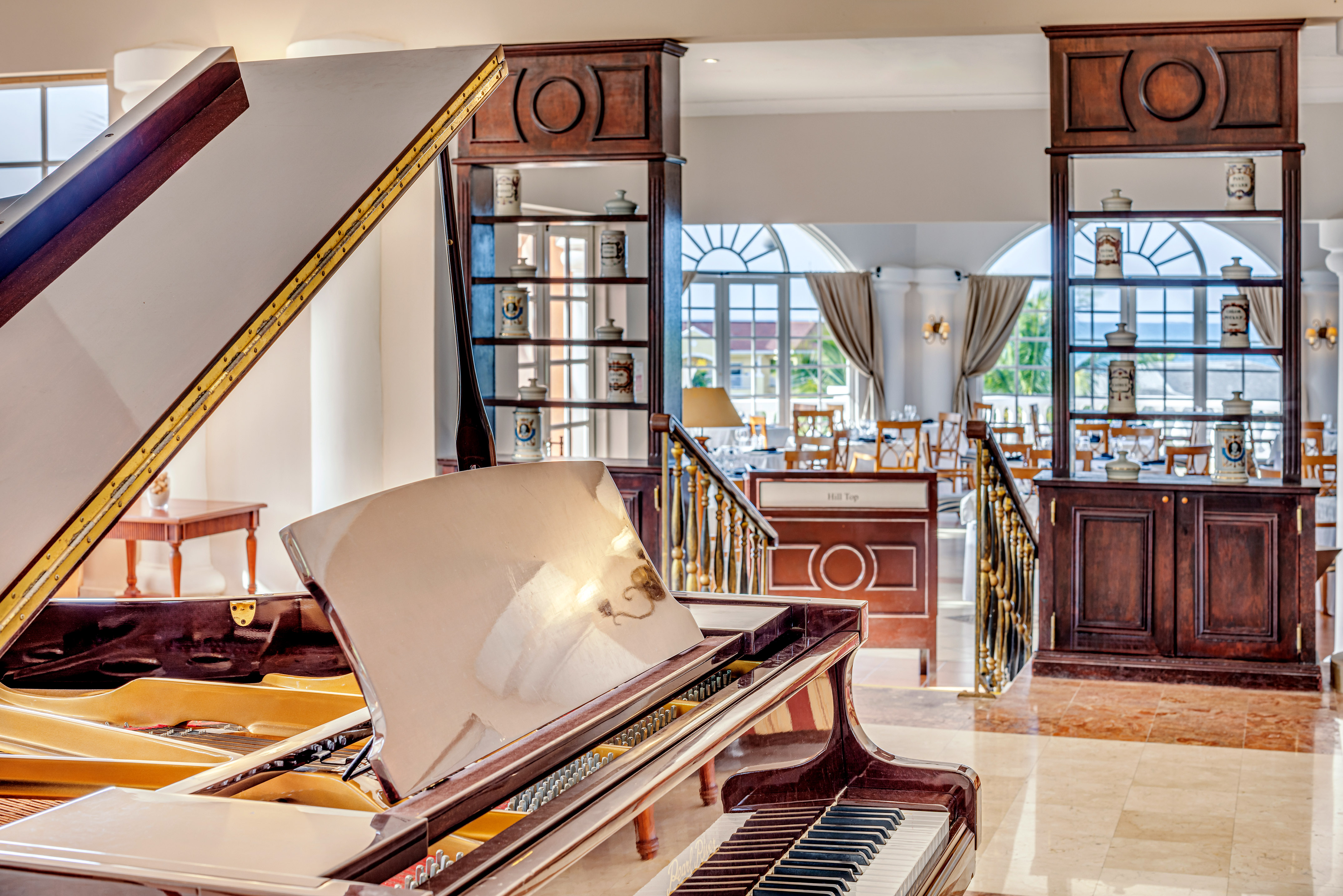 a piano in a room with a staircase and windows