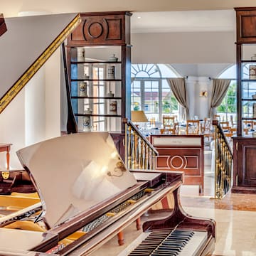 a piano in a room with a staircase and windows