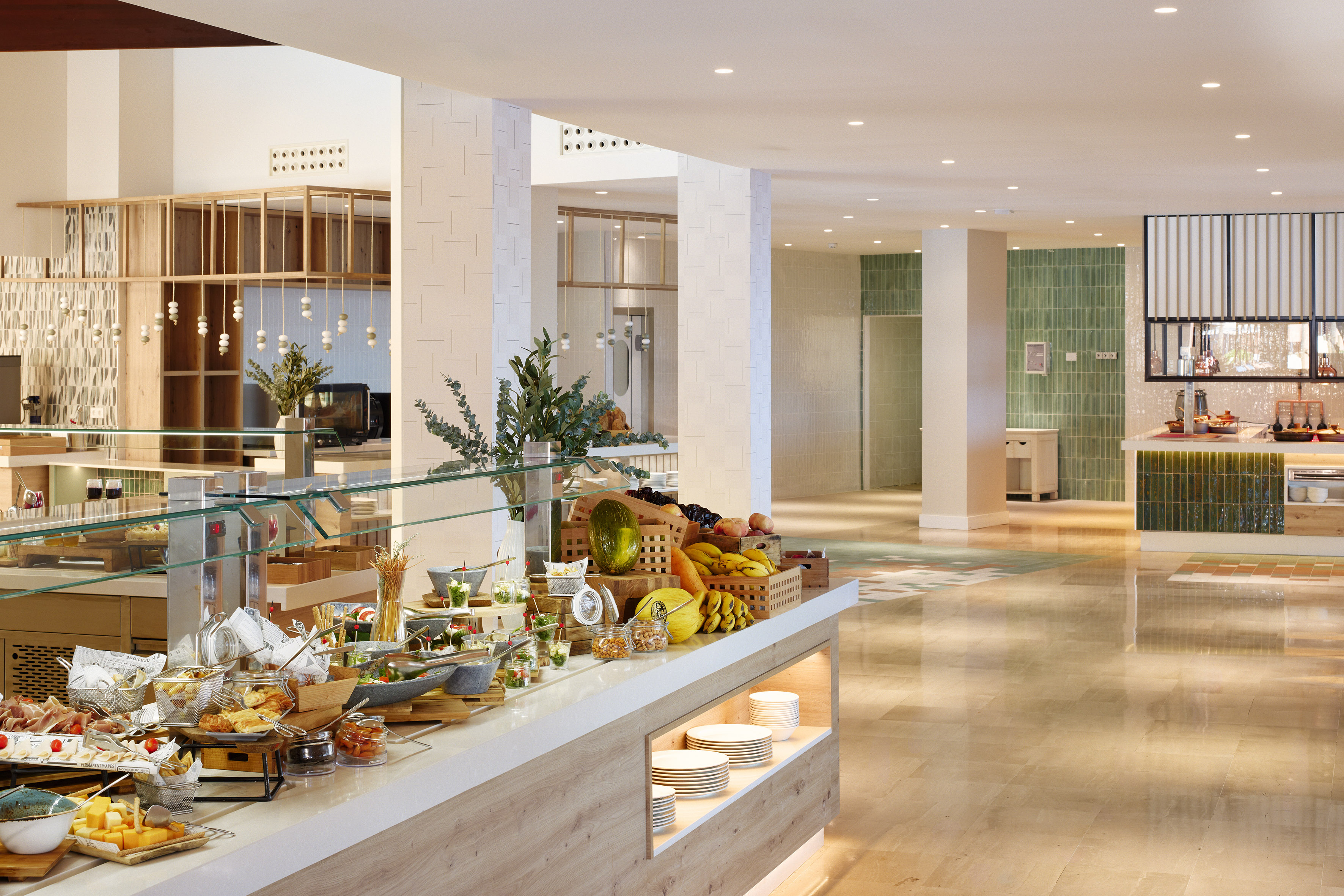 Hotel buffet with fresh fruit, cheeses, charcuterie, and pastries in a modern setting.