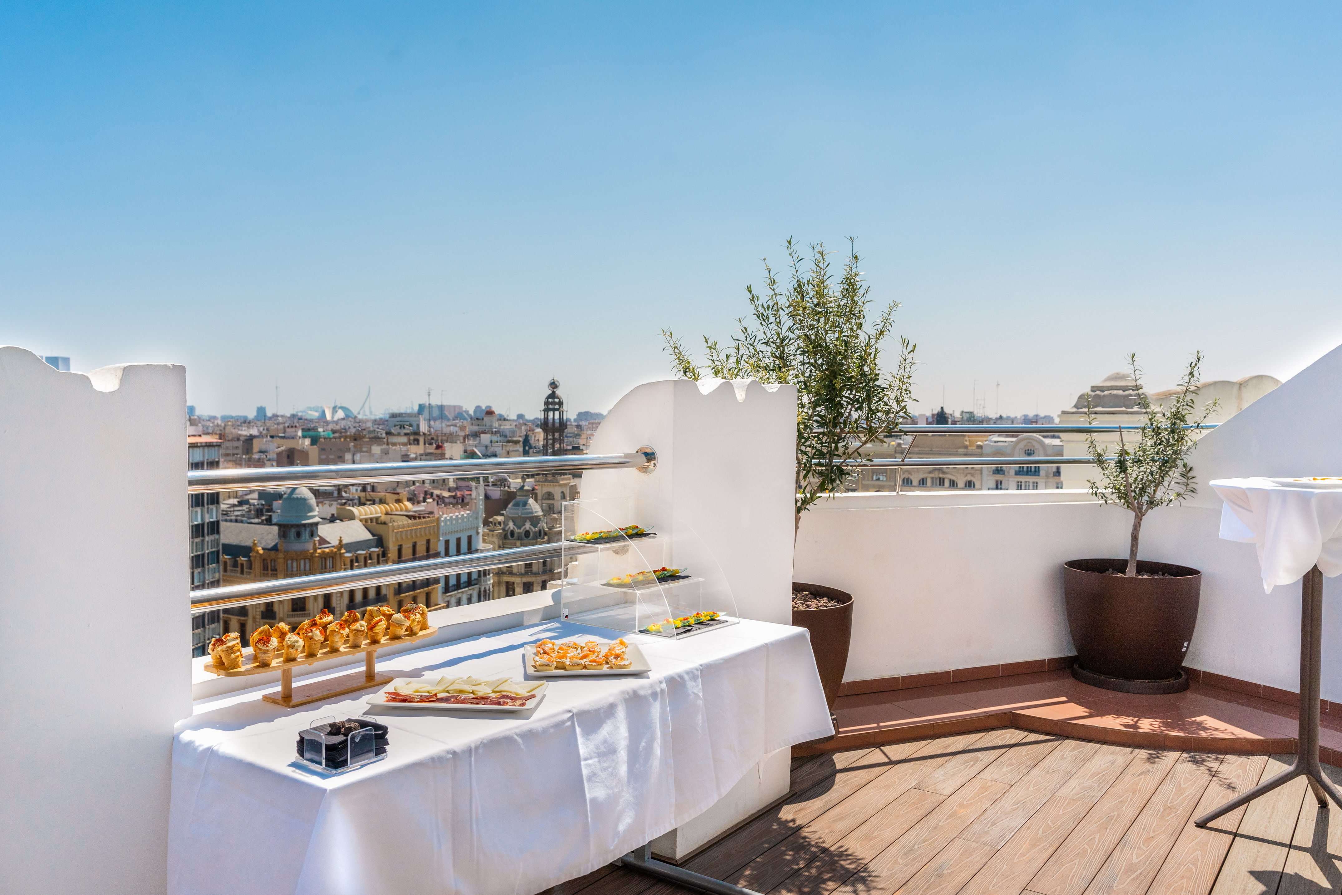City view from a sunny rooftop terrace with a catering spread of tapas.