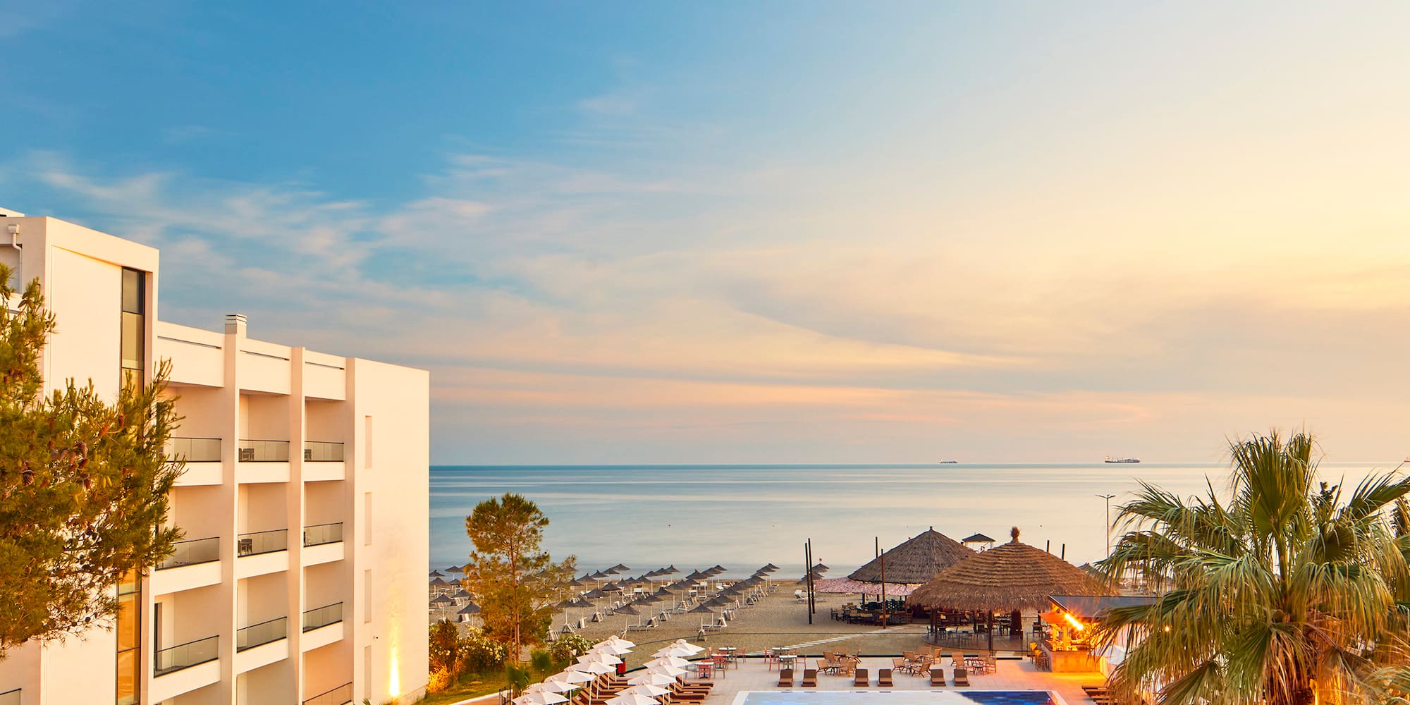 a swimming pool with umbrellas and chairs by a building