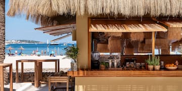 un bar con tetto di paglia e una spiaggia sullo sfondo