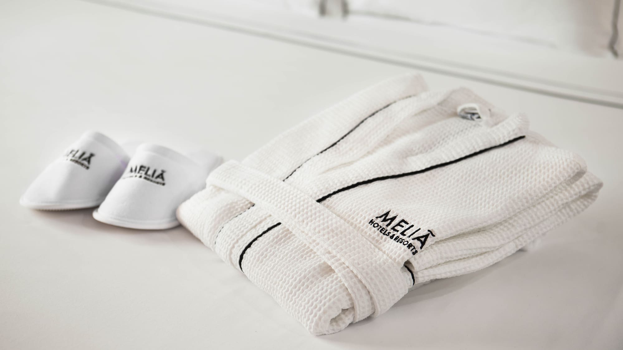 a white robe and slippers on a bed