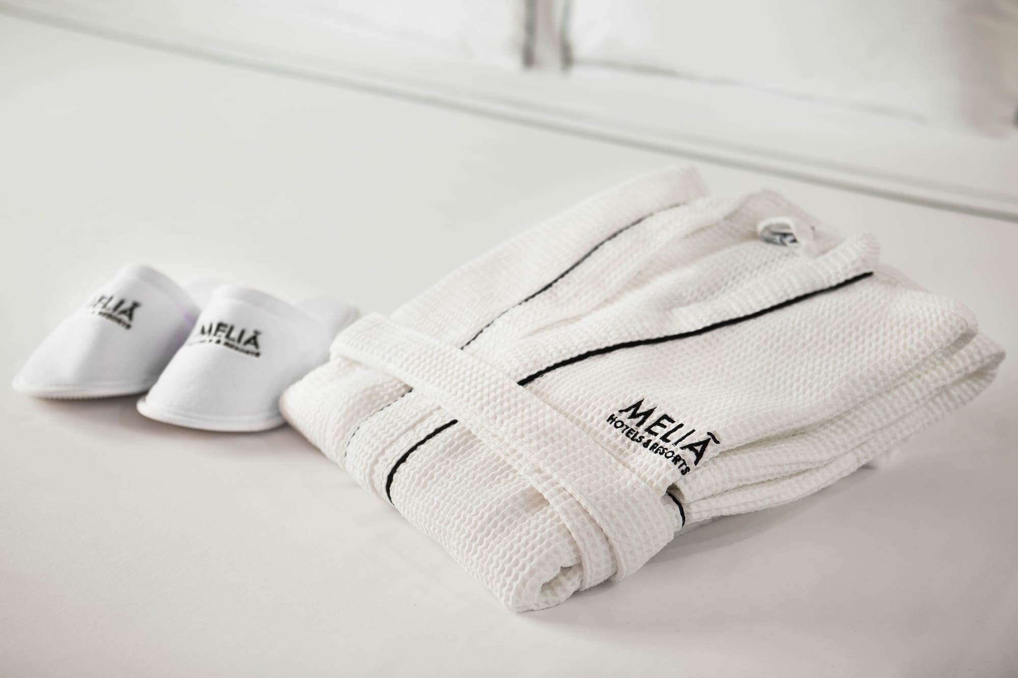 a white robe and slippers on a bed