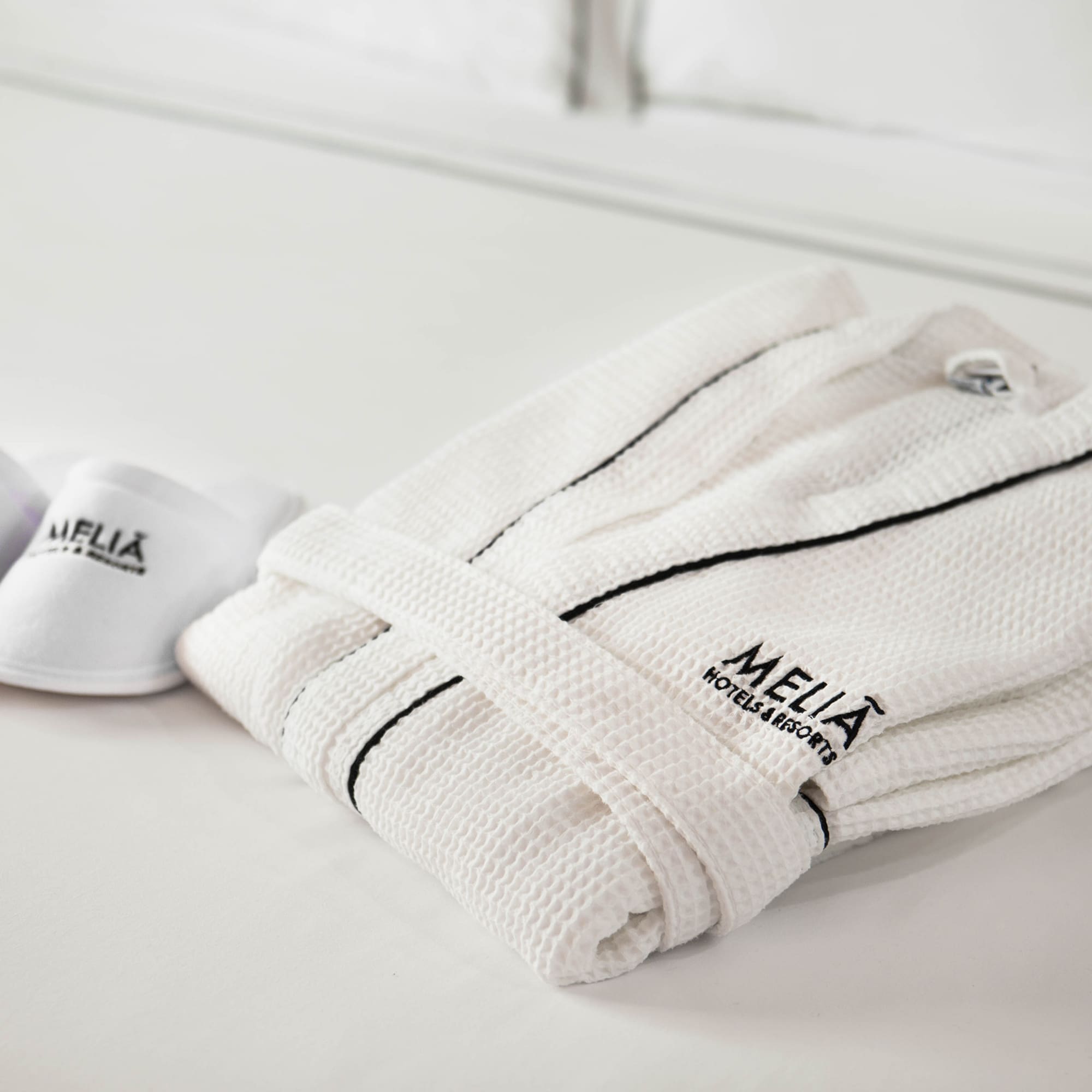 a white robe and slippers on a bed